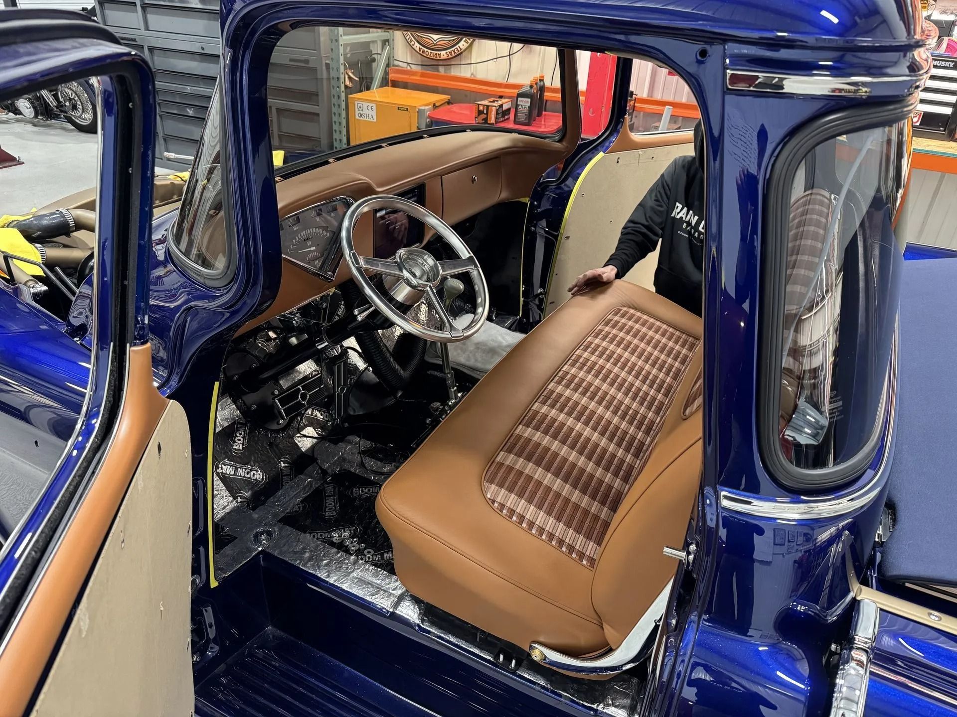 A man is sitting in the driver 's seat of a blue truck.