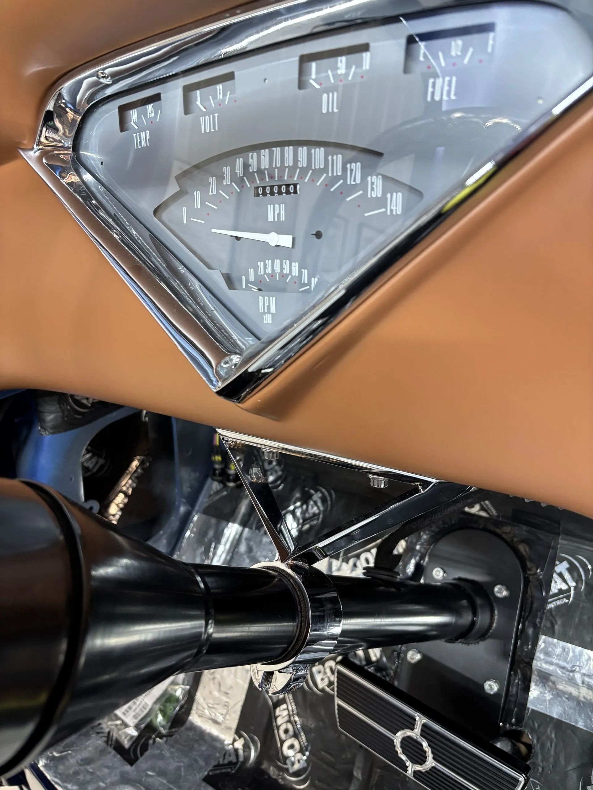 A close up of a car dashboard with a speedometer and a steering wheel.