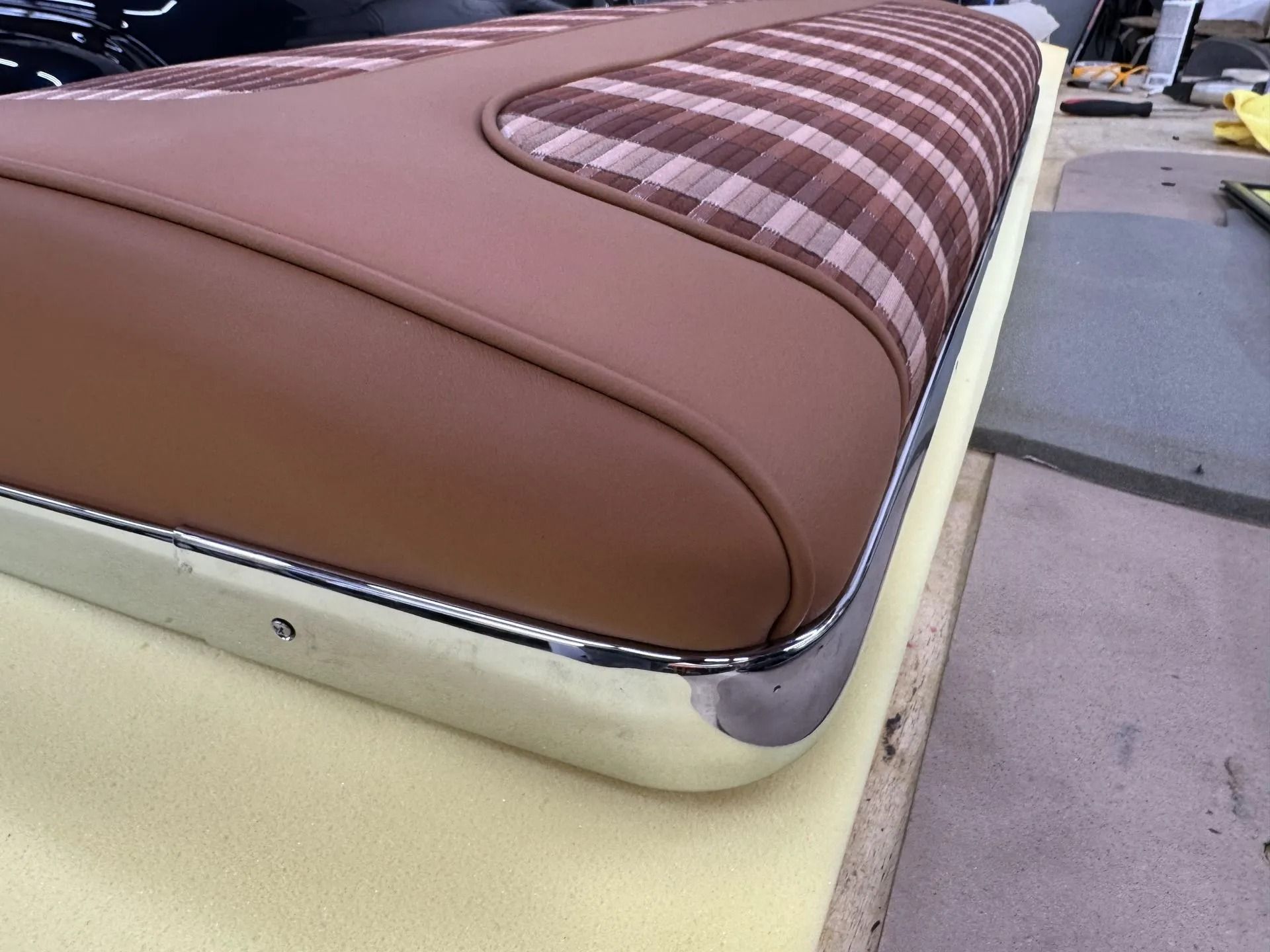 A brown and pink plaid seat cushion with a chrome trim