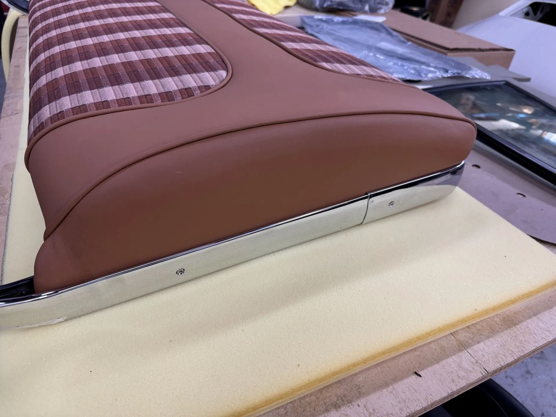 A brown cushion is sitting on top of a piece of foam on a table.