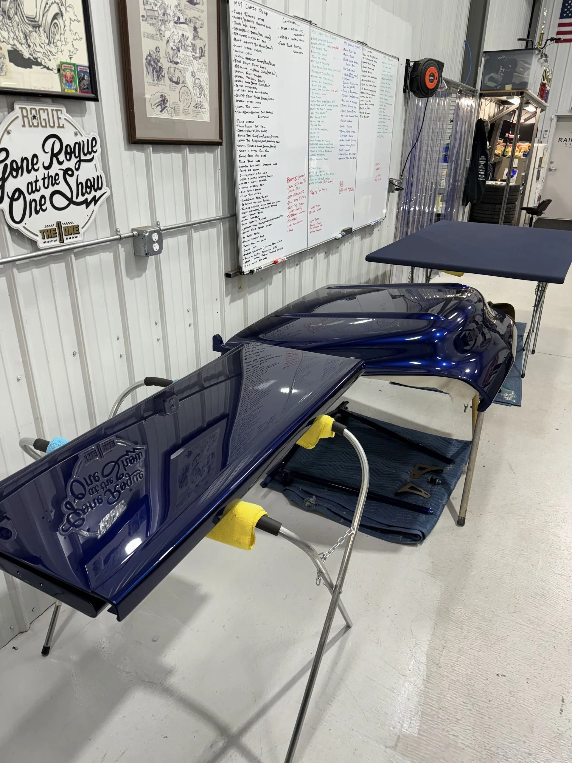 A blue car is sitting on a table in a garage.