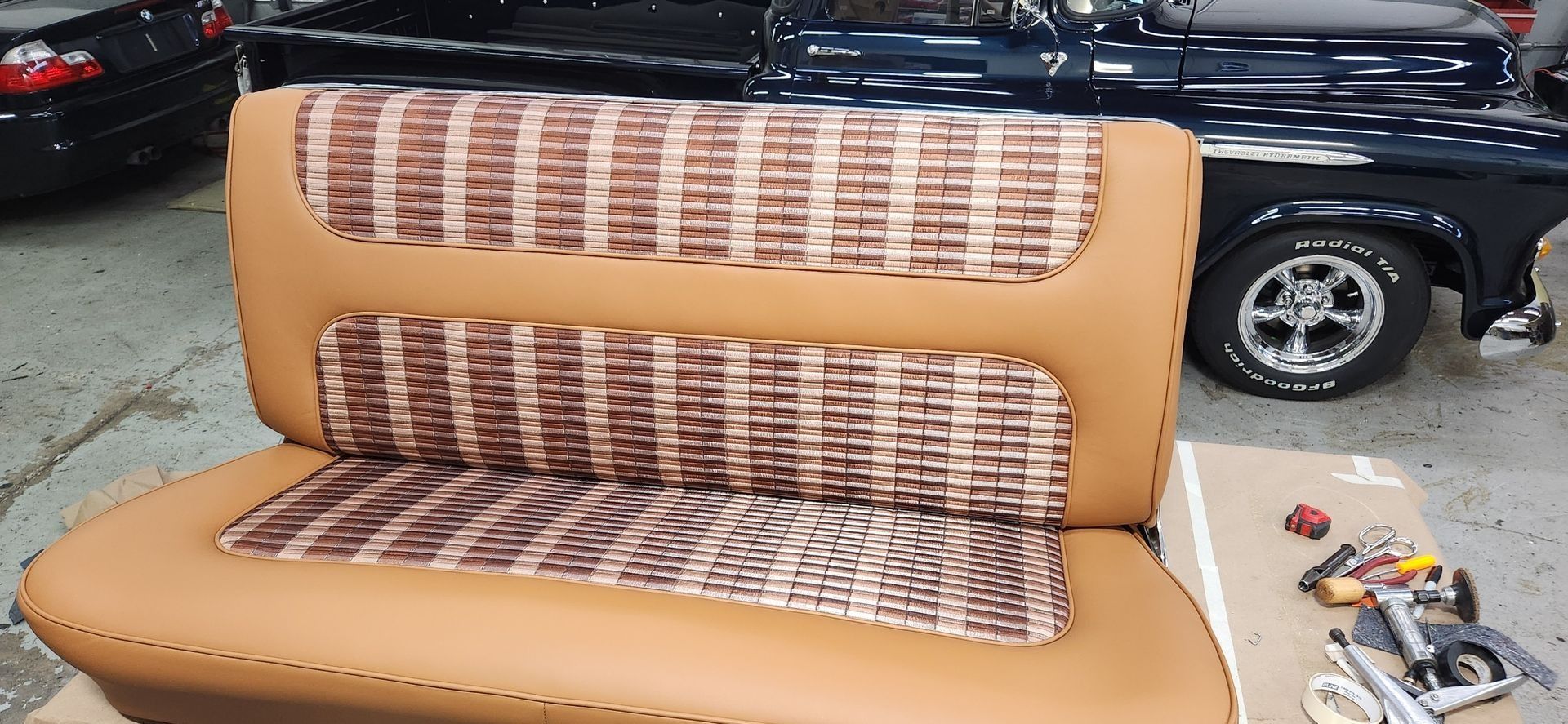A couch is sitting in front of a truck in a garage.