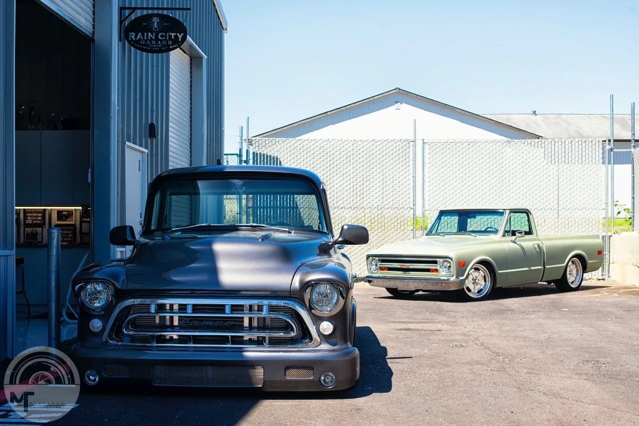 Two pickup trucks are parked in front of a building.