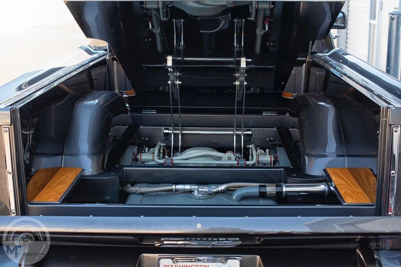 The trunk of a car with the hood up and the engine visible.