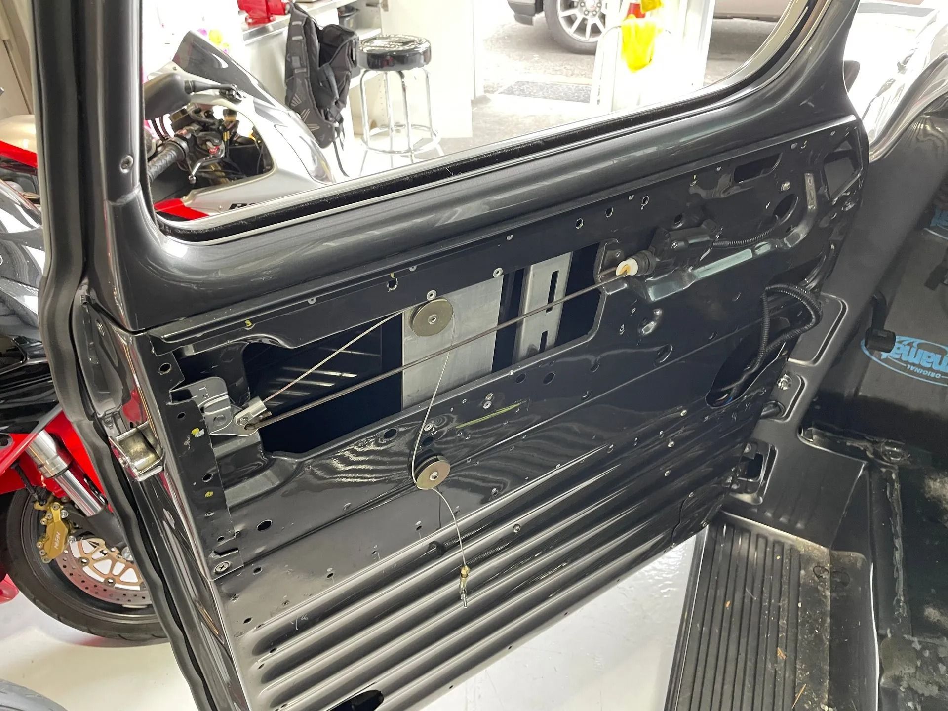 A close up of a car door with a motorcycle in the background.