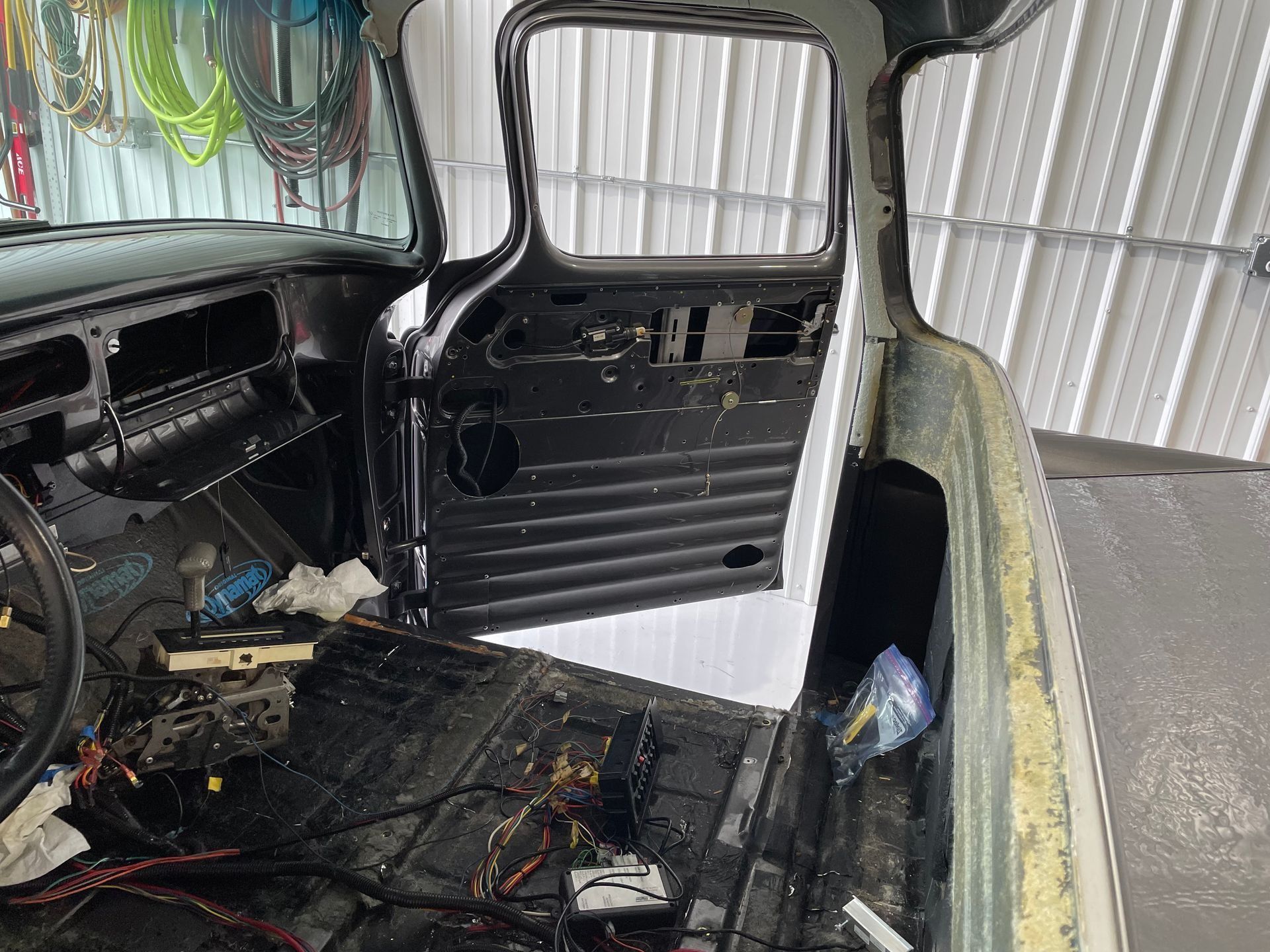 A car is being restored in a garage with the door open.