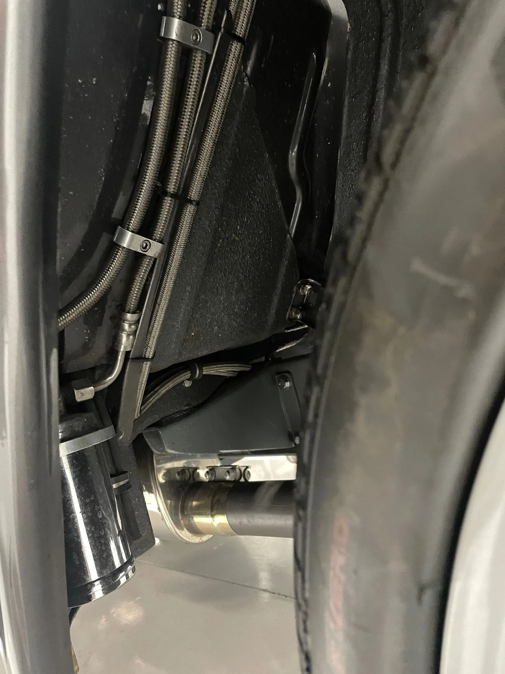 A close up of a car fender with hose attached to it.
