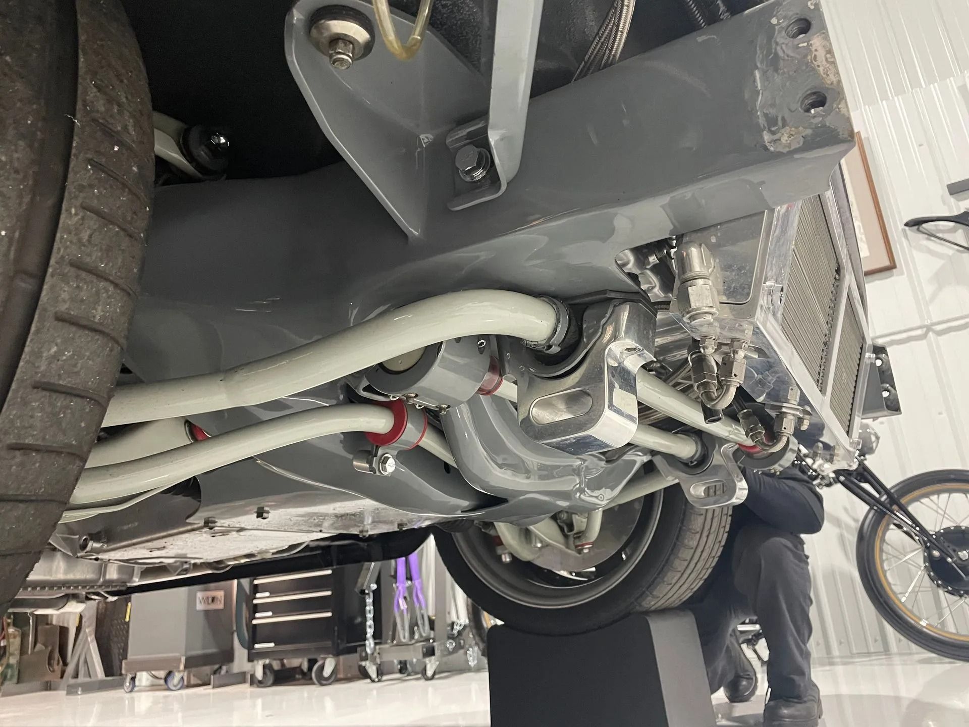 A man is working on the underside of a car in a garage.