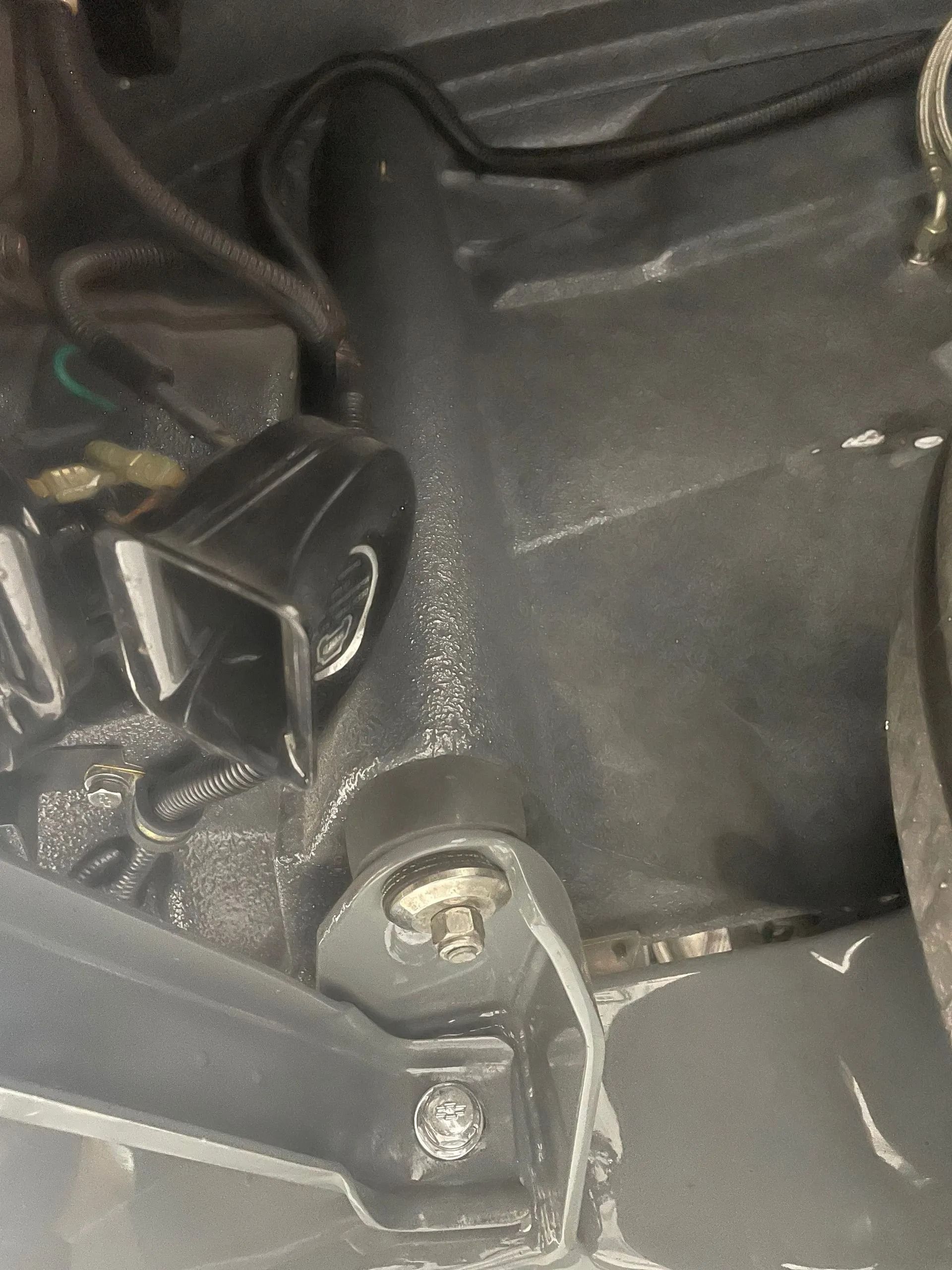 A close up of a car engine with a screw in it.