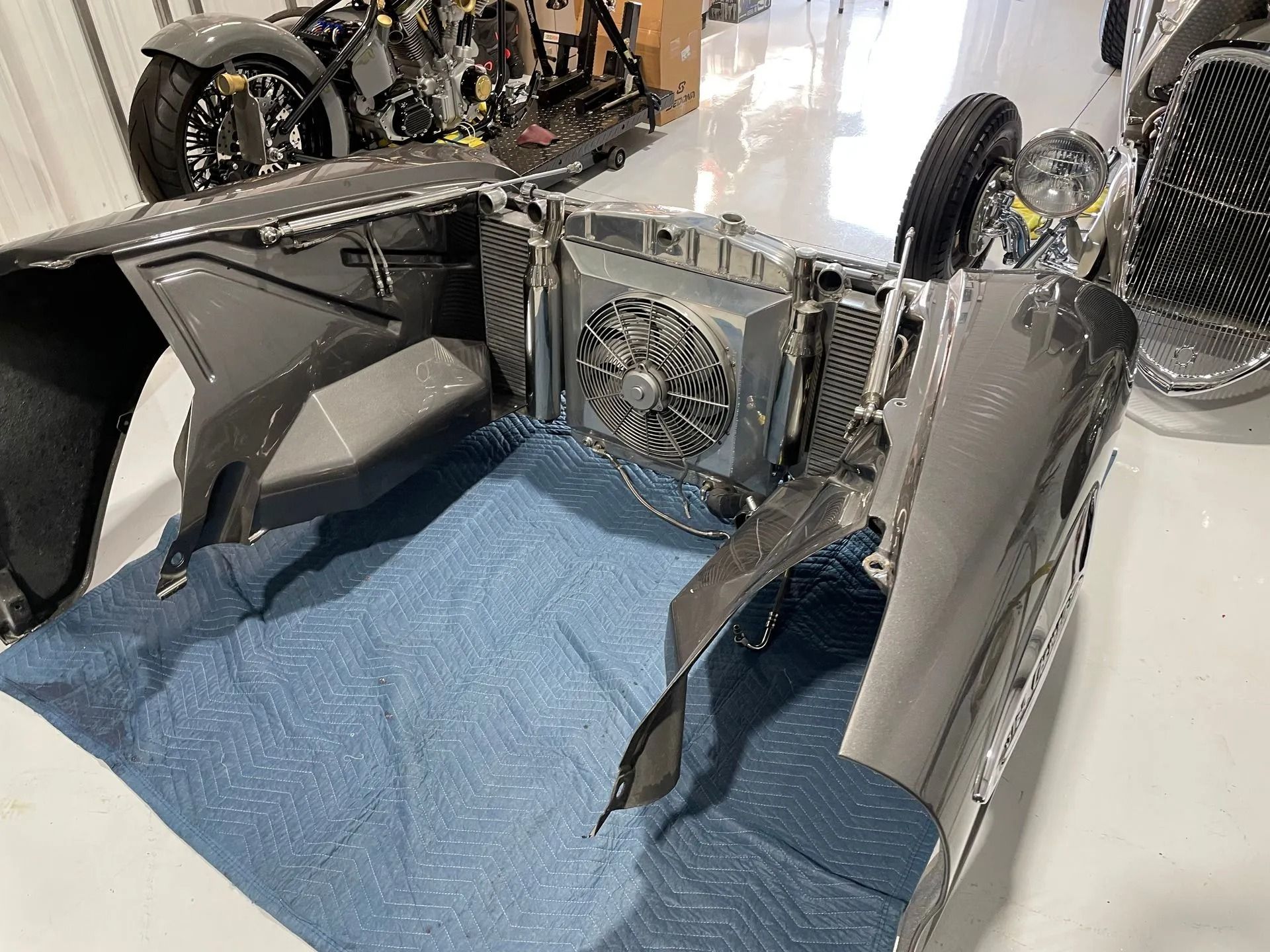 A car is sitting on top of a blue carpet in a garage.