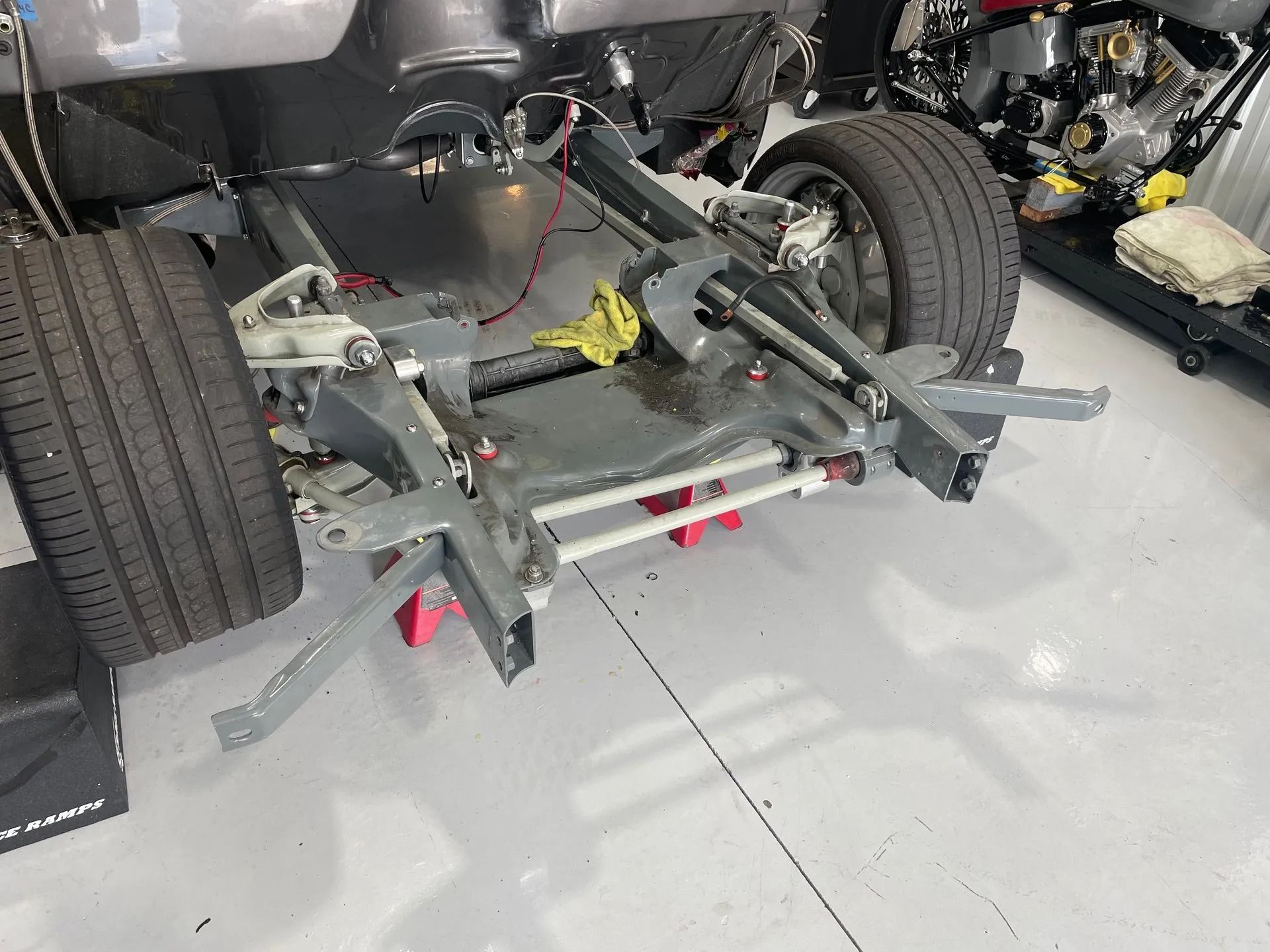 A car chassis is sitting on a lift in a garage.