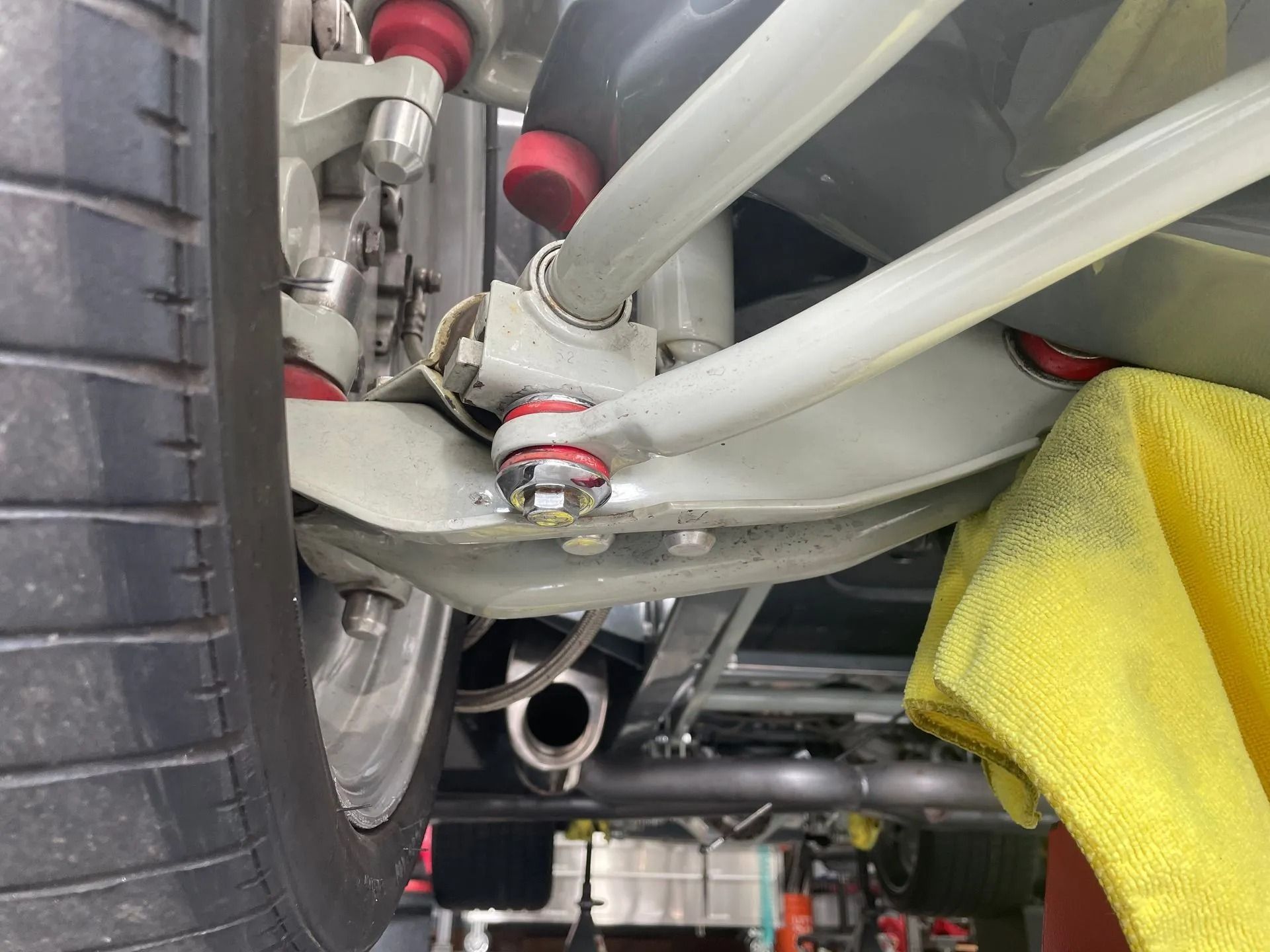 A close up of the underside of a car with a yellow towel on the ground.