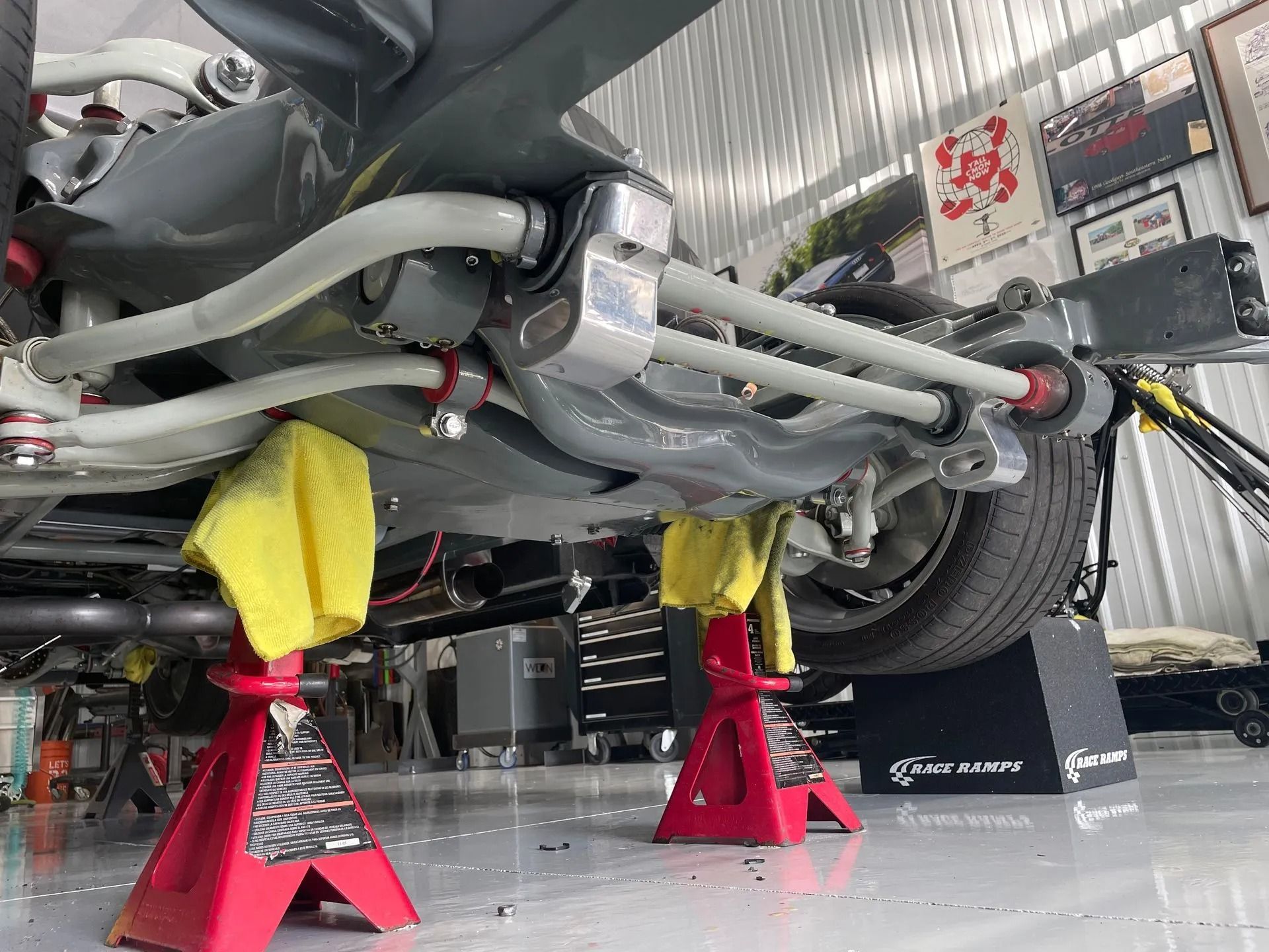 A car is sitting on jack stands in a garage.