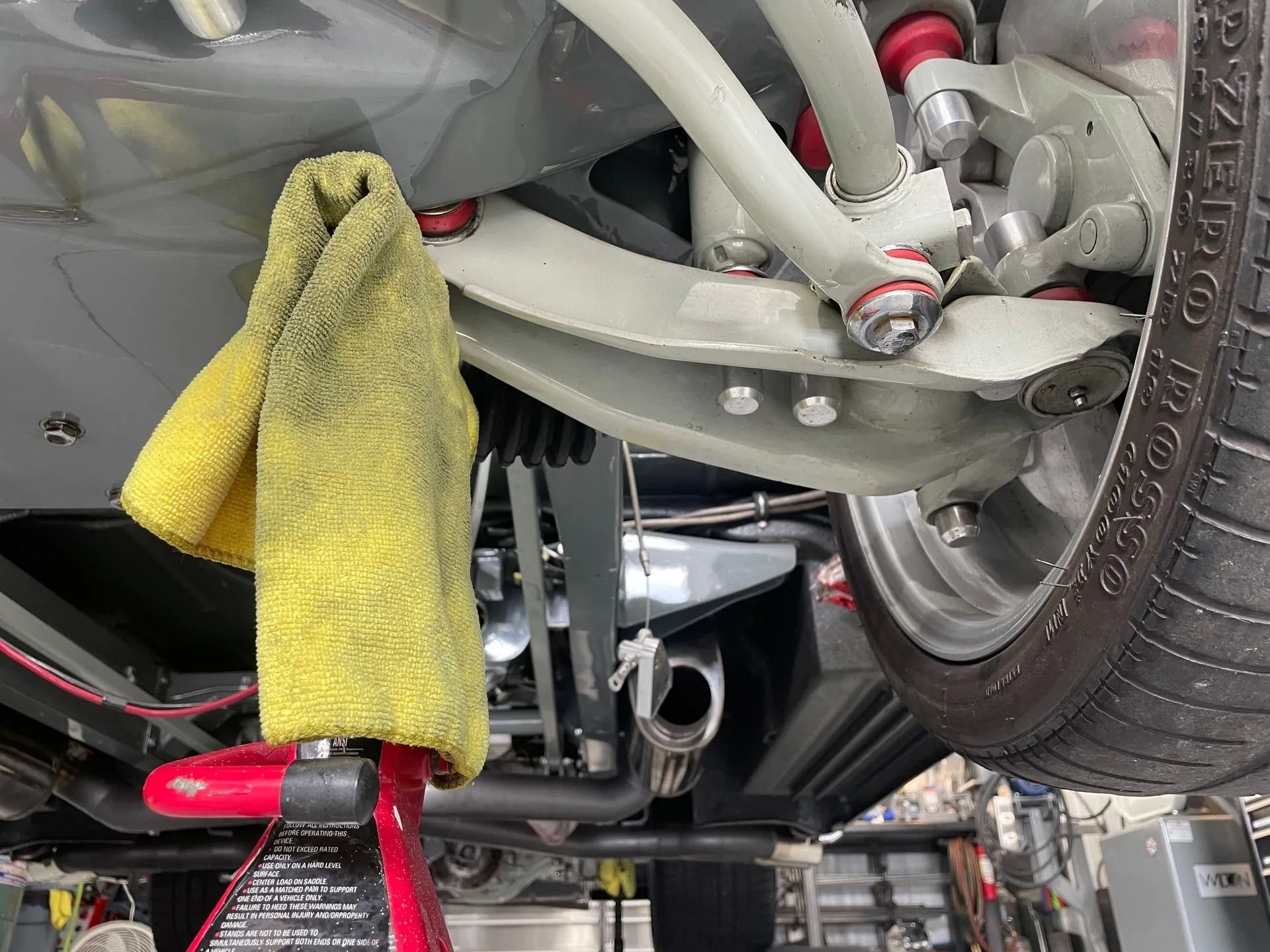 A yellow towel is hanging from the underside of a car.
