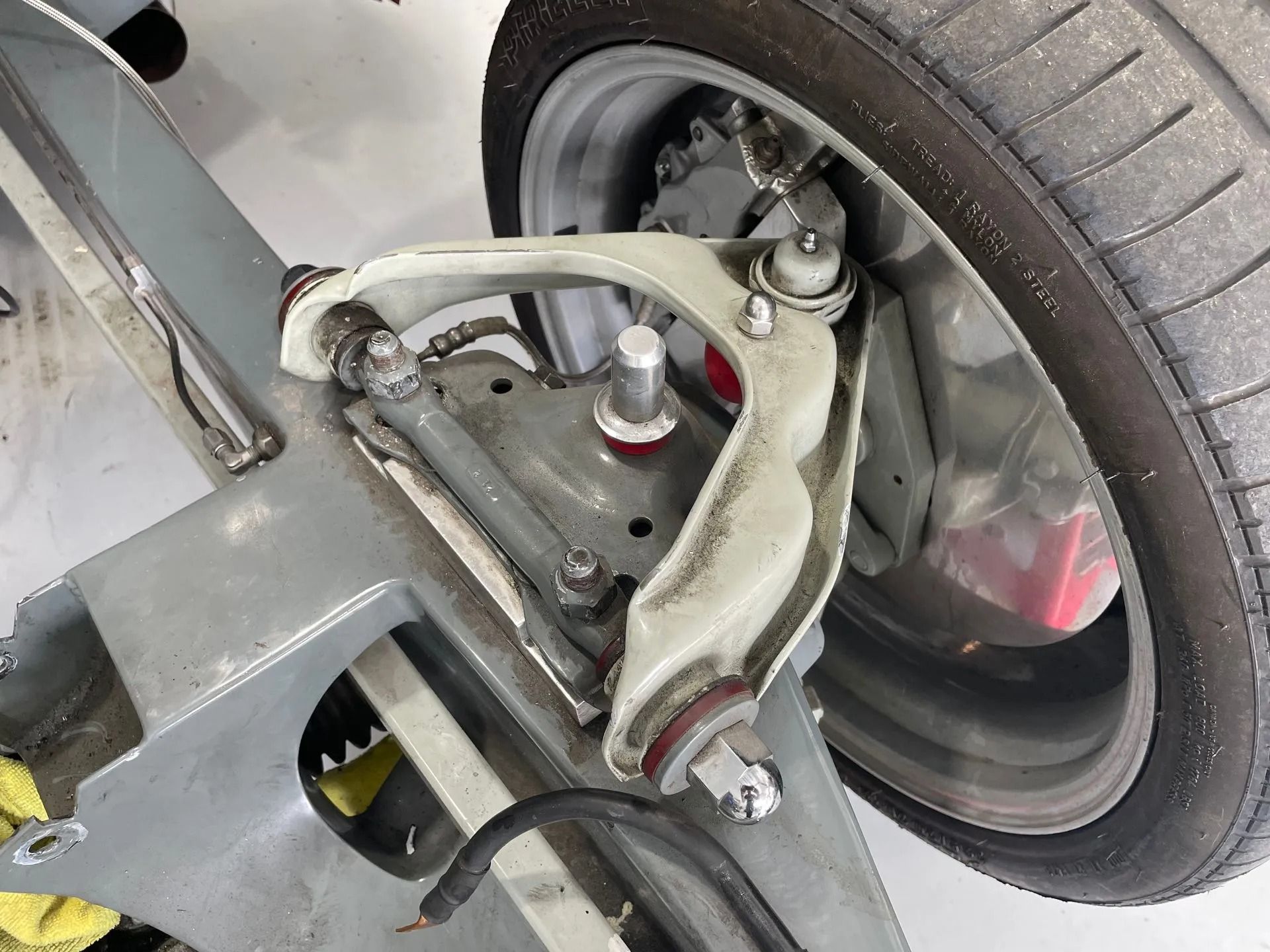 A close up of a car suspension with a tire in the background