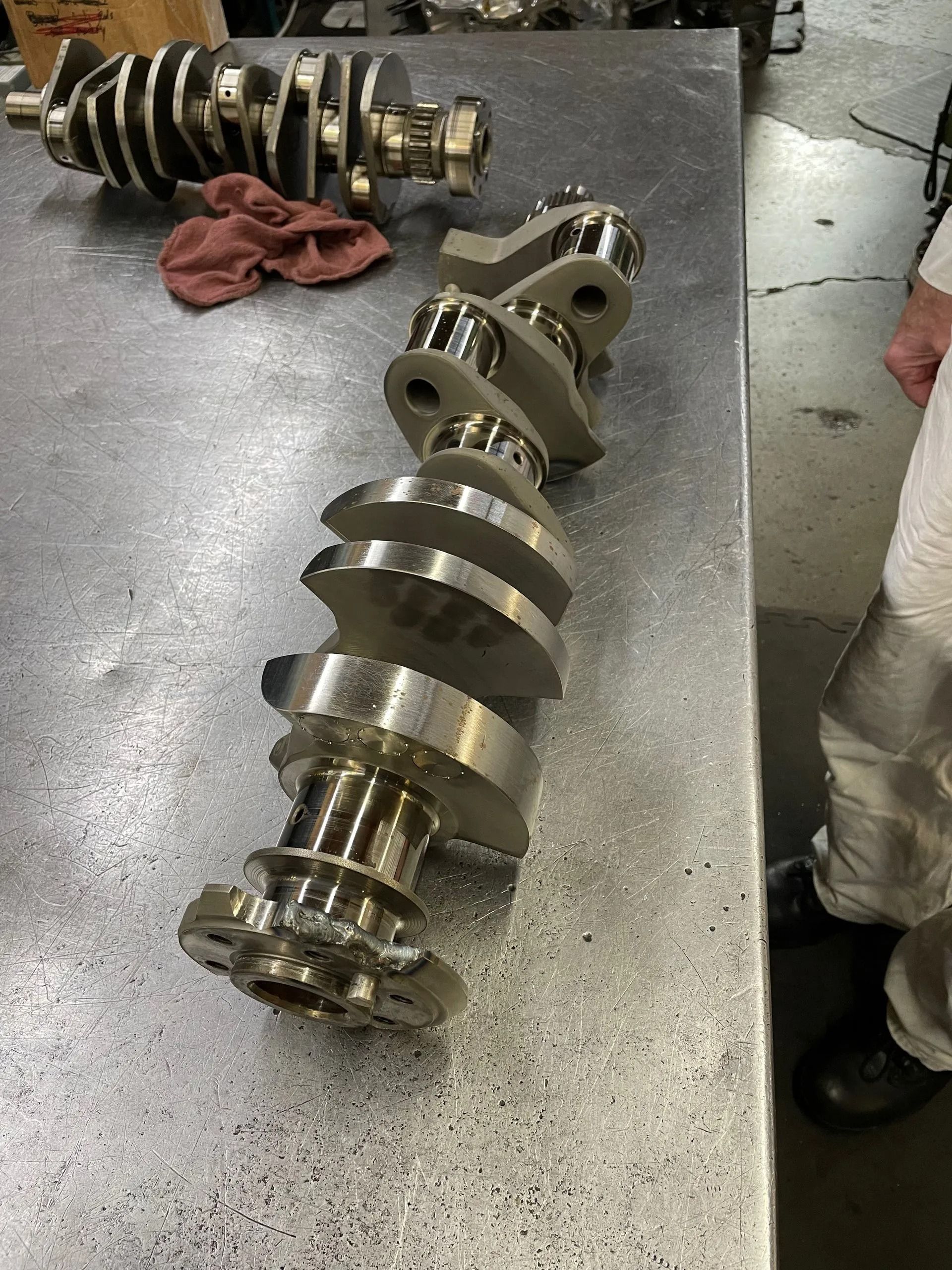 Two crankshafts are sitting on a table in a garage.