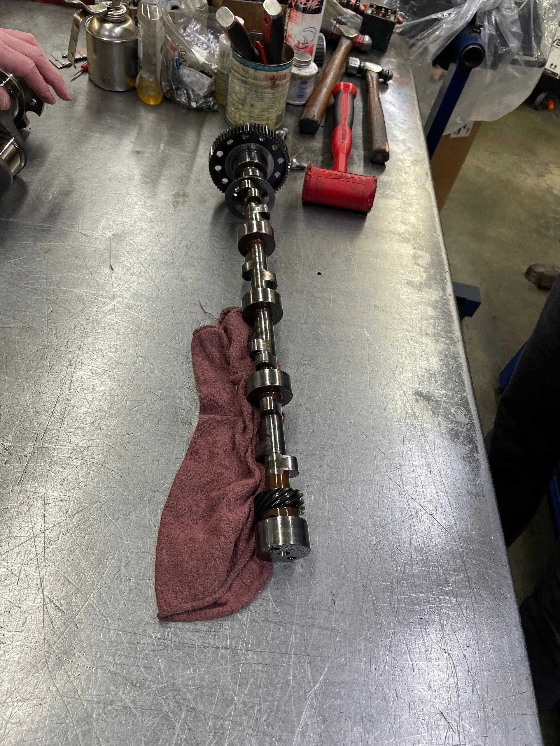 A camshaft is sitting on a towel on a metal table.