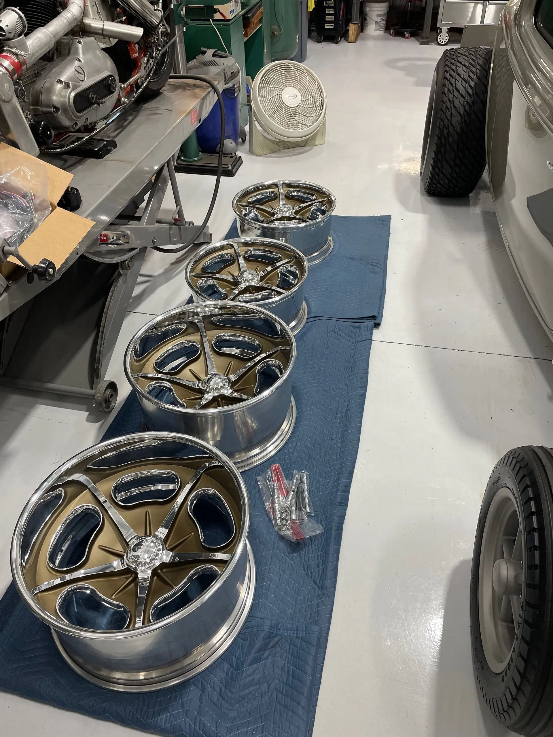 A row of wheels are lined up on a blue mat in a garage