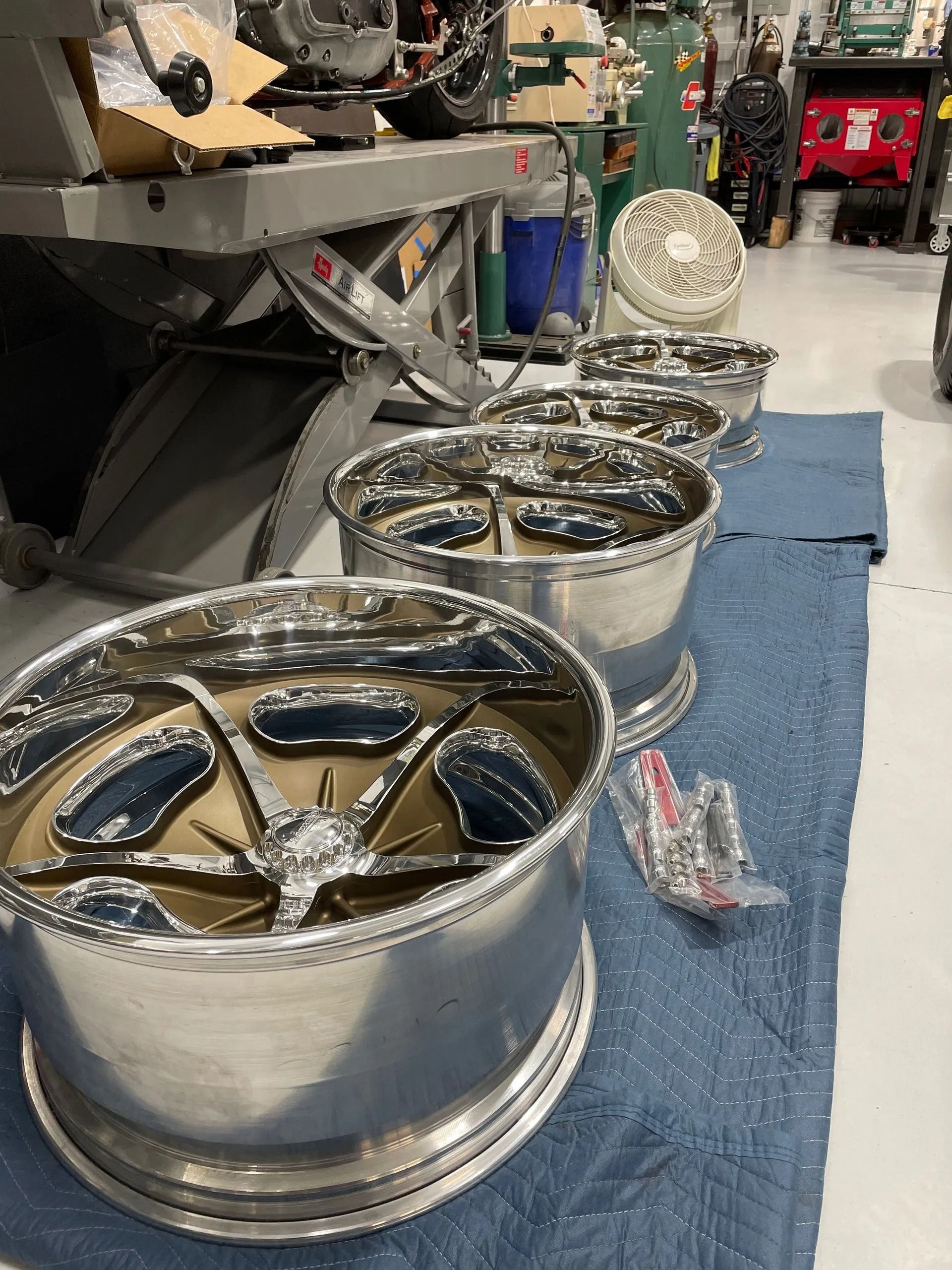 A row of wheels are sitting on a blue mat in a garage.