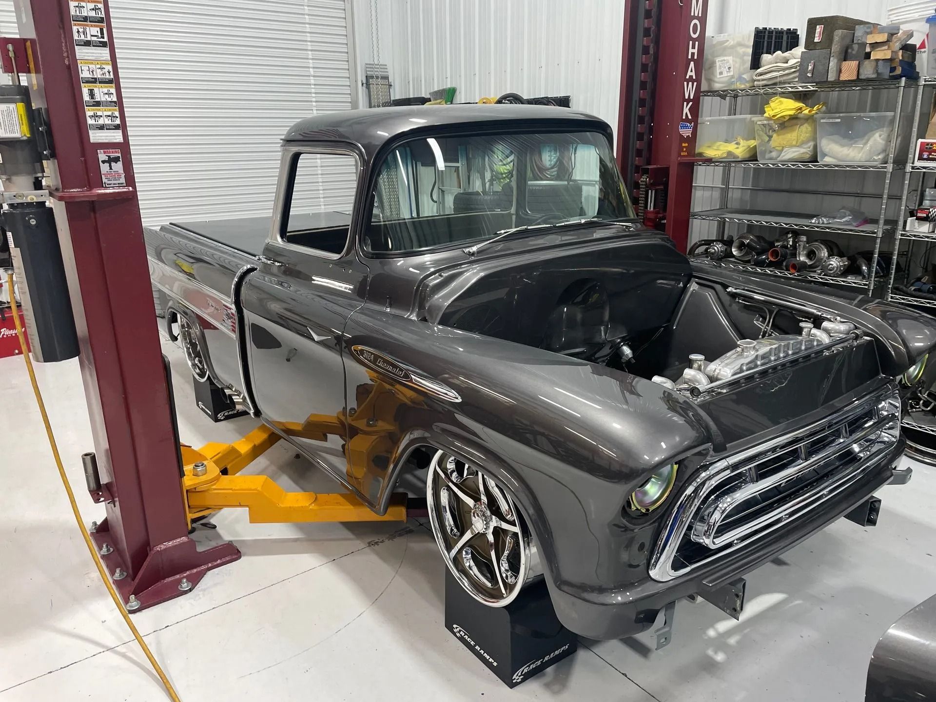 A truck is sitting on a lift in a garage.