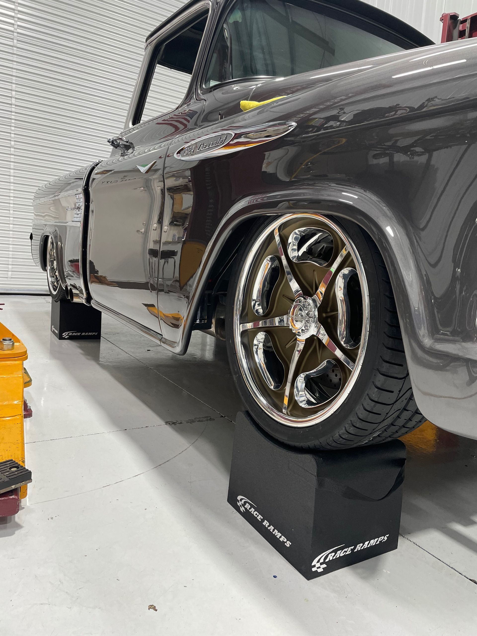 A gray truck is parked on a ramp in a garage.
