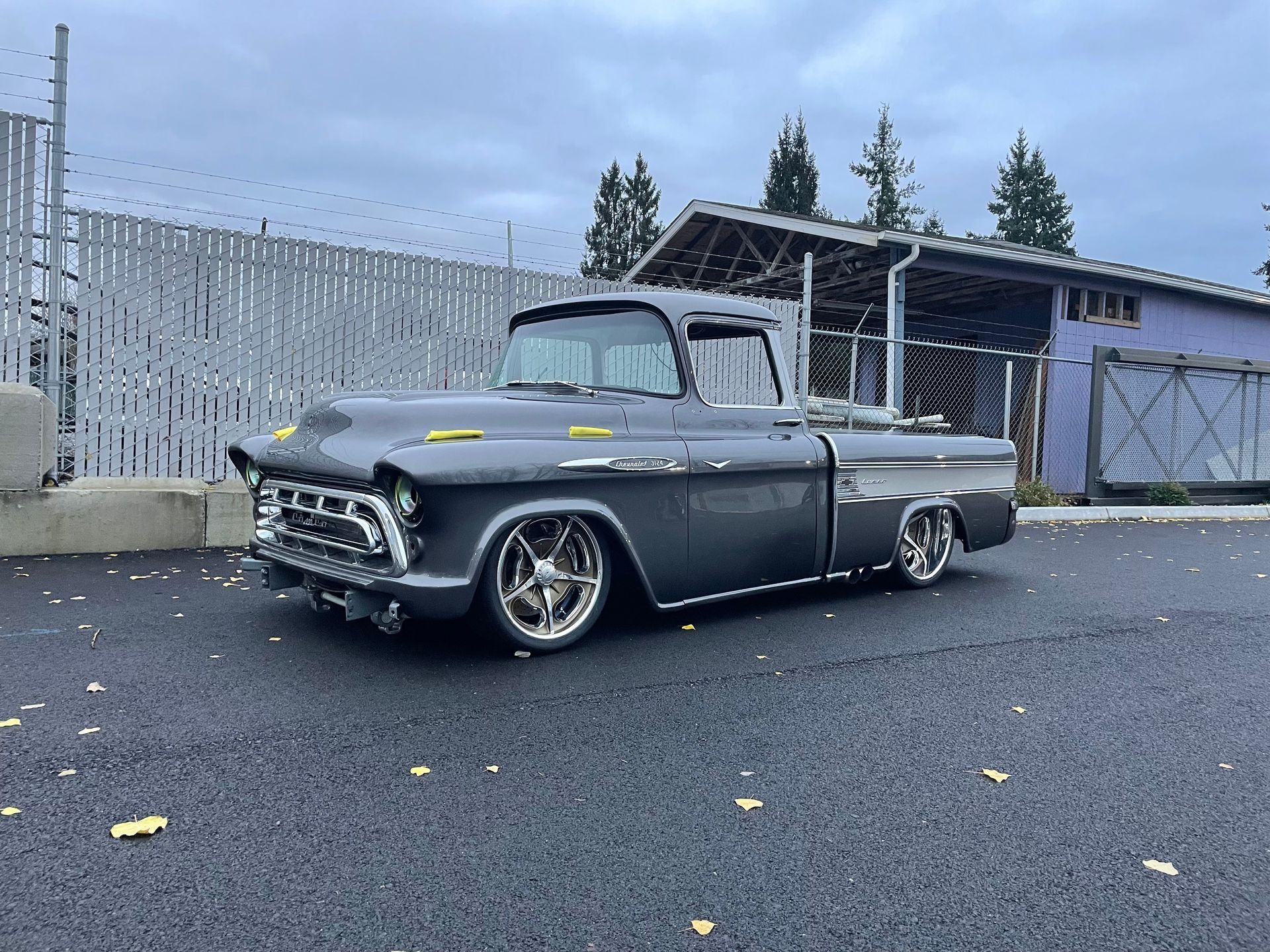 A gray truck is parked on the side of the road in front of a building.