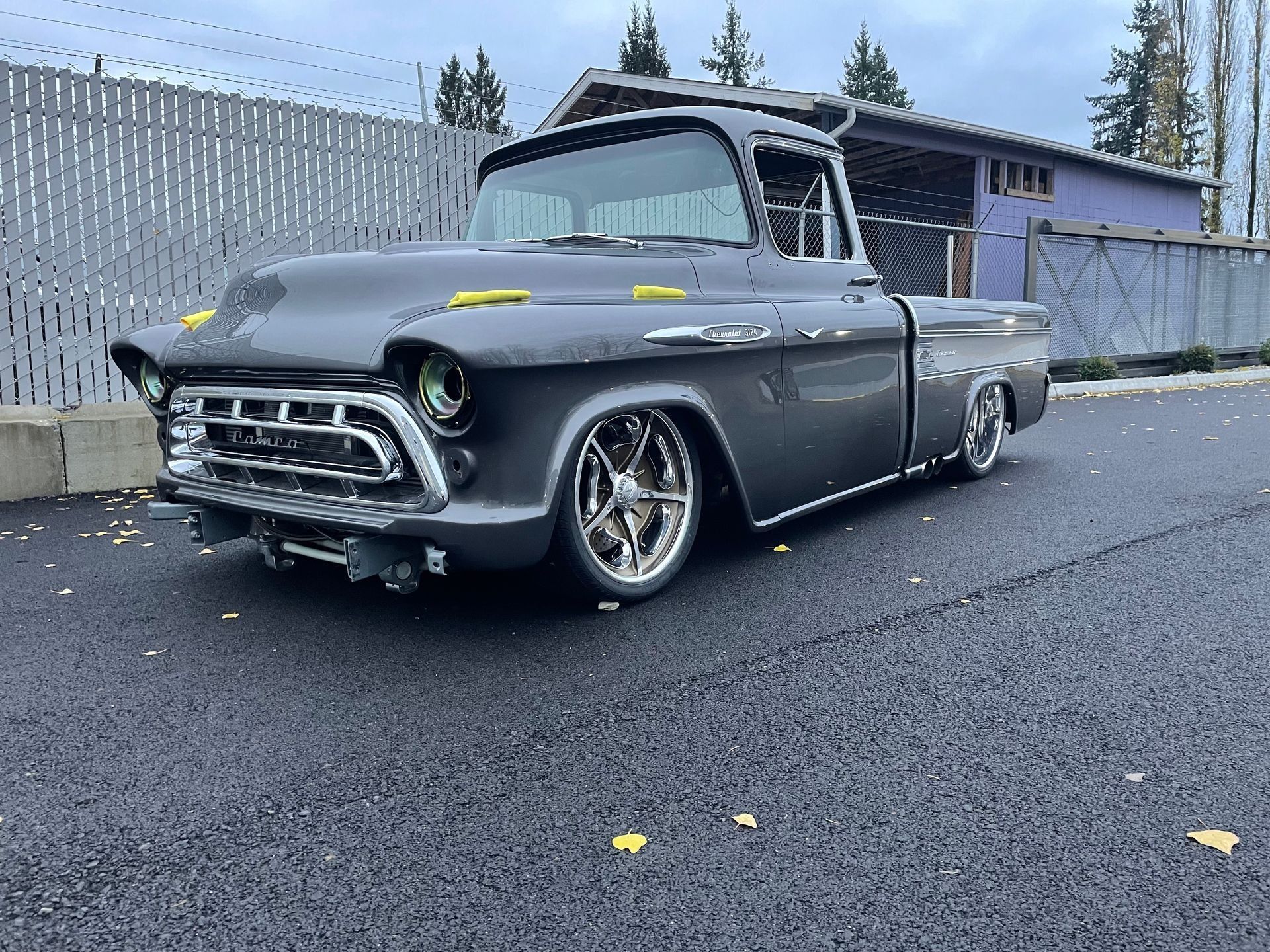 A gray truck is parked on the side of the road in front of a building.