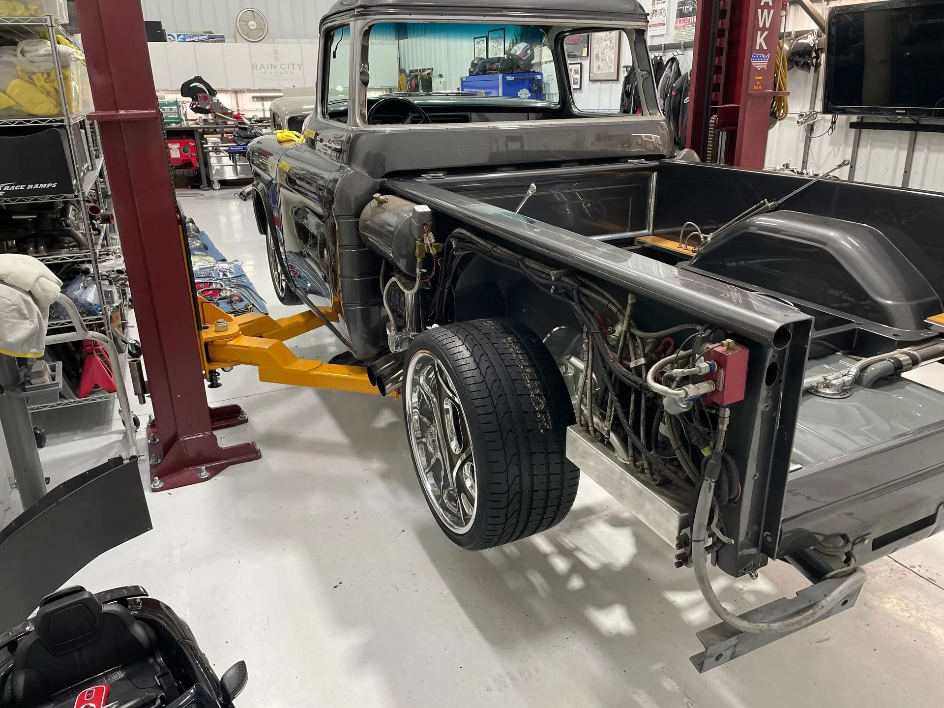 A black truck is sitting on a lift in a garage.