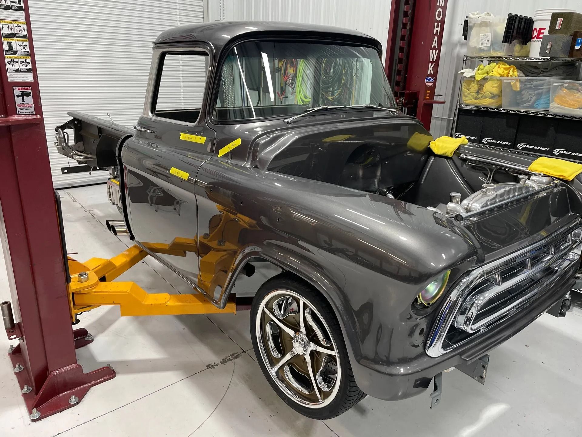 A gray truck is sitting on a lift in a garage.