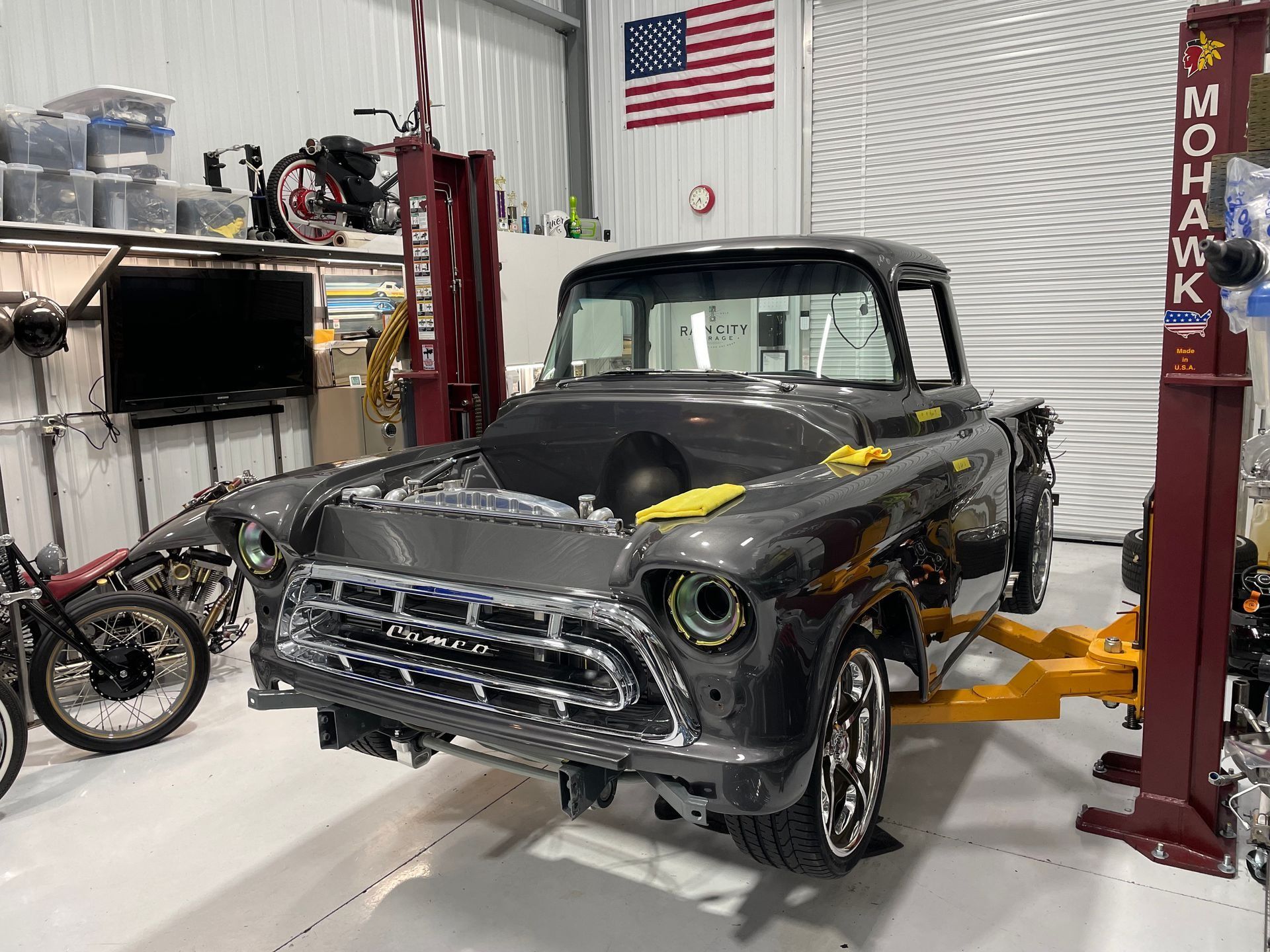 A gray truck is sitting on a lift in a garage.