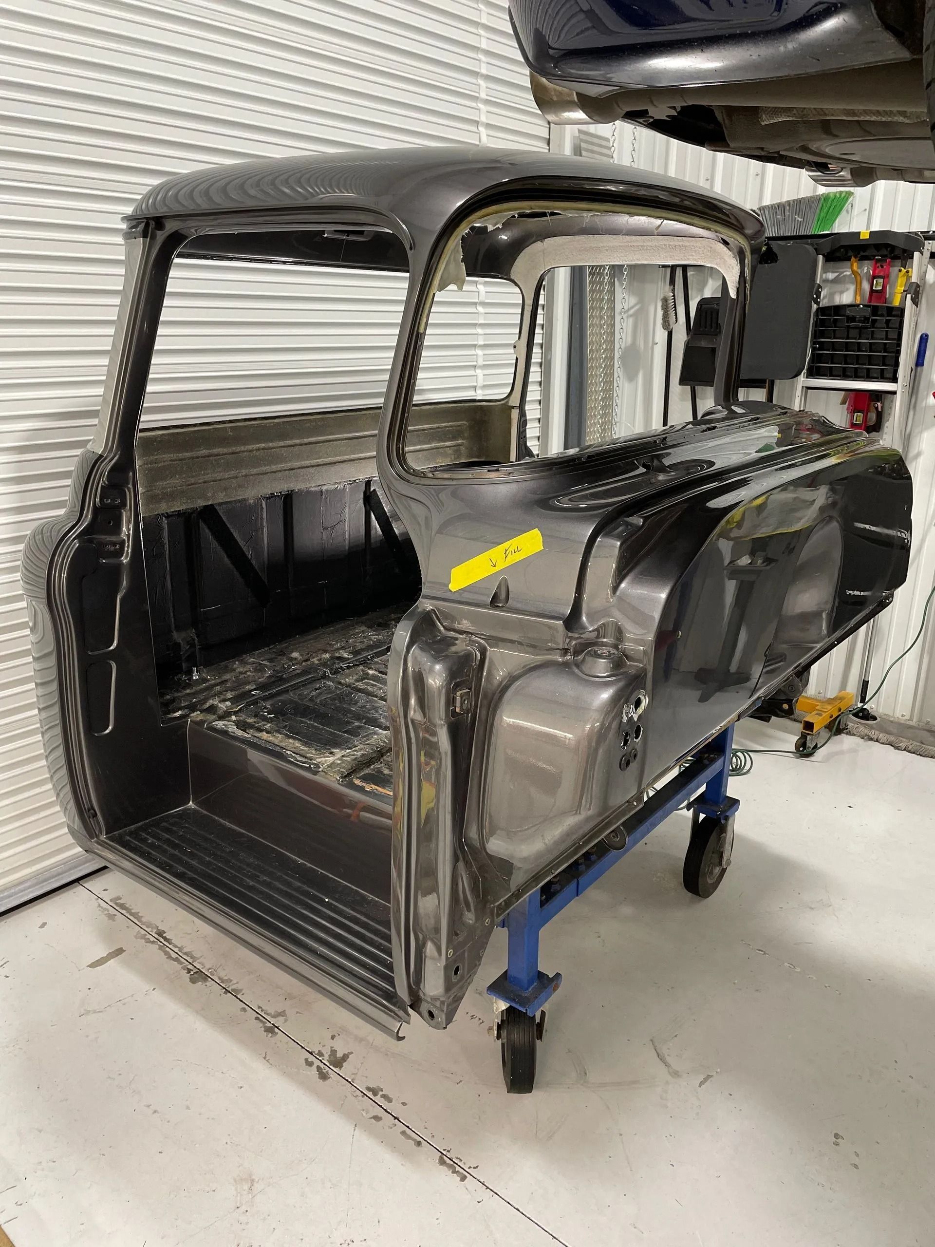 A truck cab is sitting on a cart in a garage.
