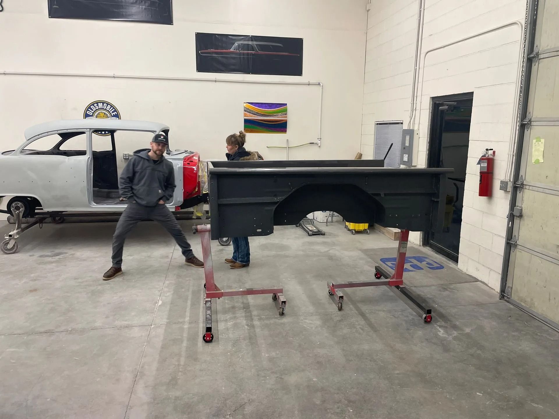 Two men are standing next to a truck bed in a garage.