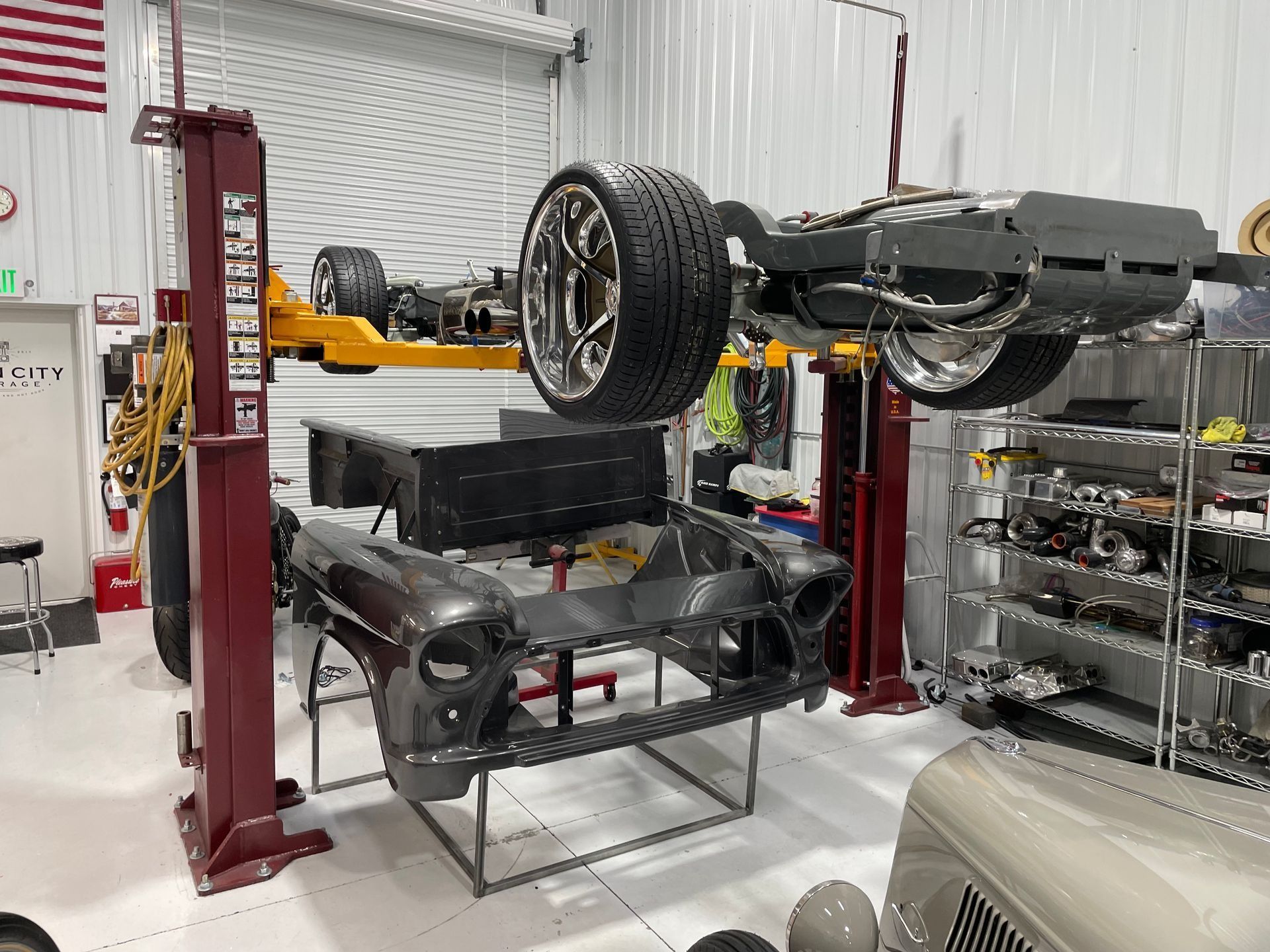 A car is being built in a garage on a lift.