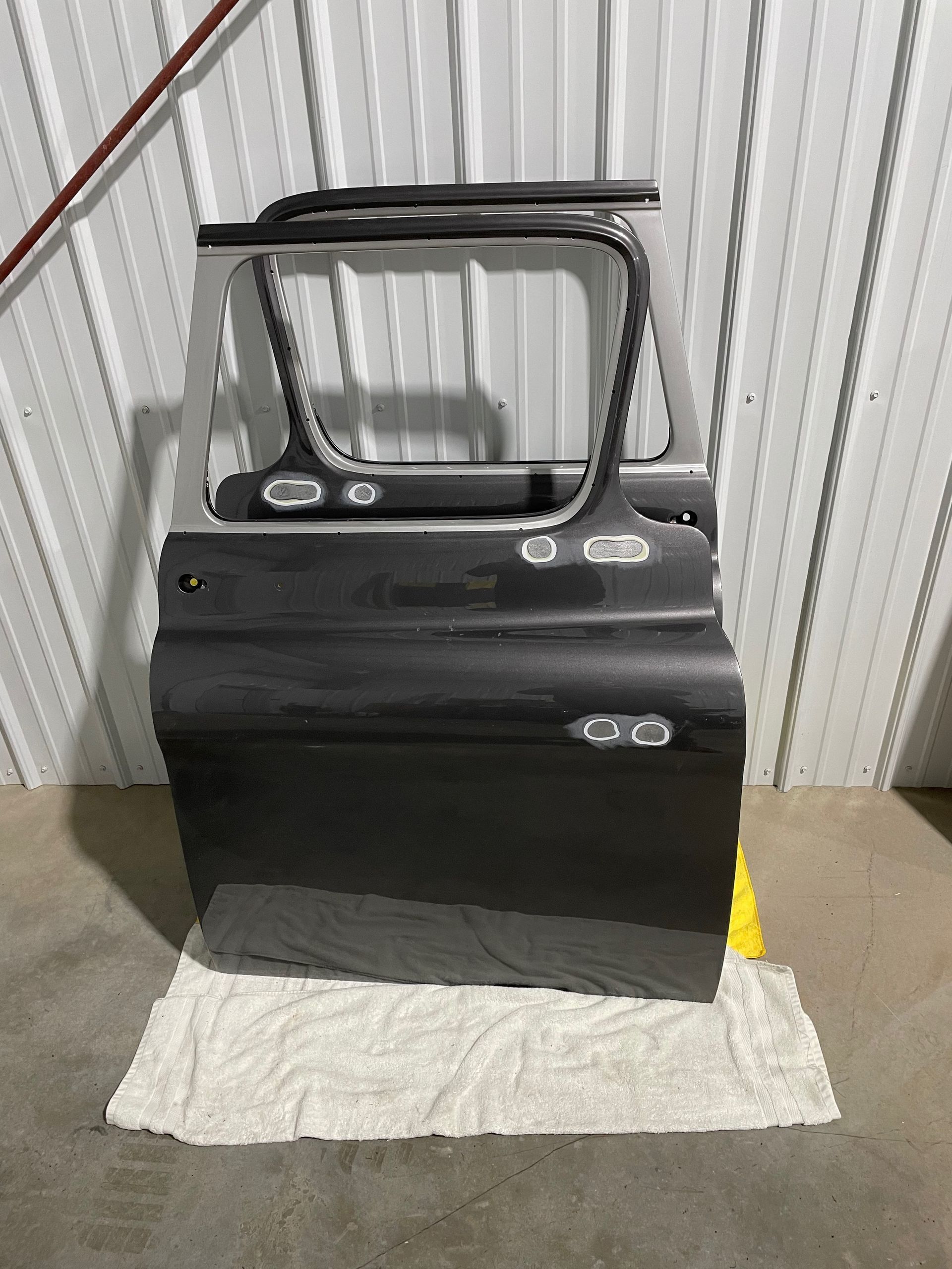 A car door is sitting on top of a towel on the floor.