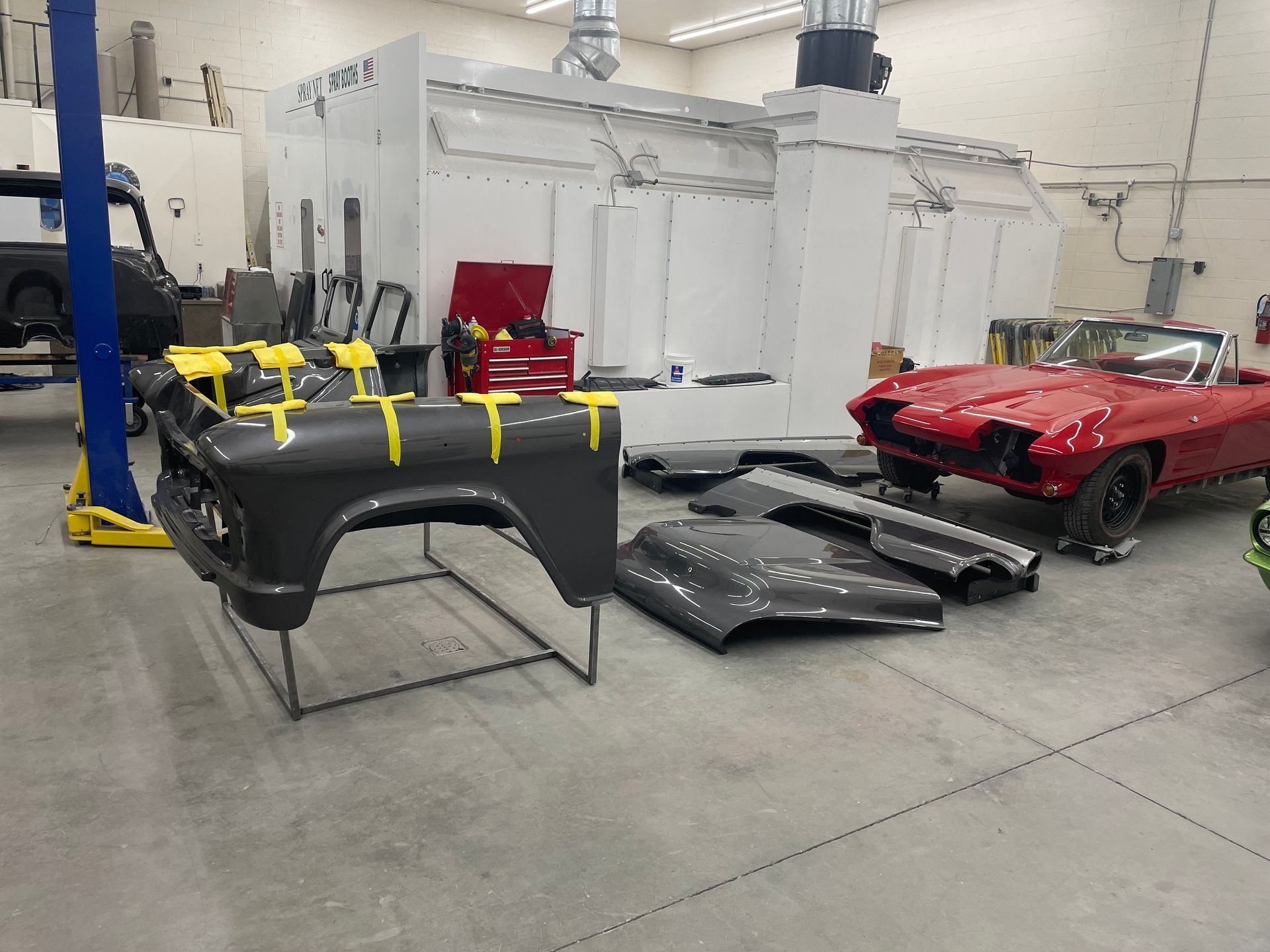 A red car is sitting next to a black car in a garage.