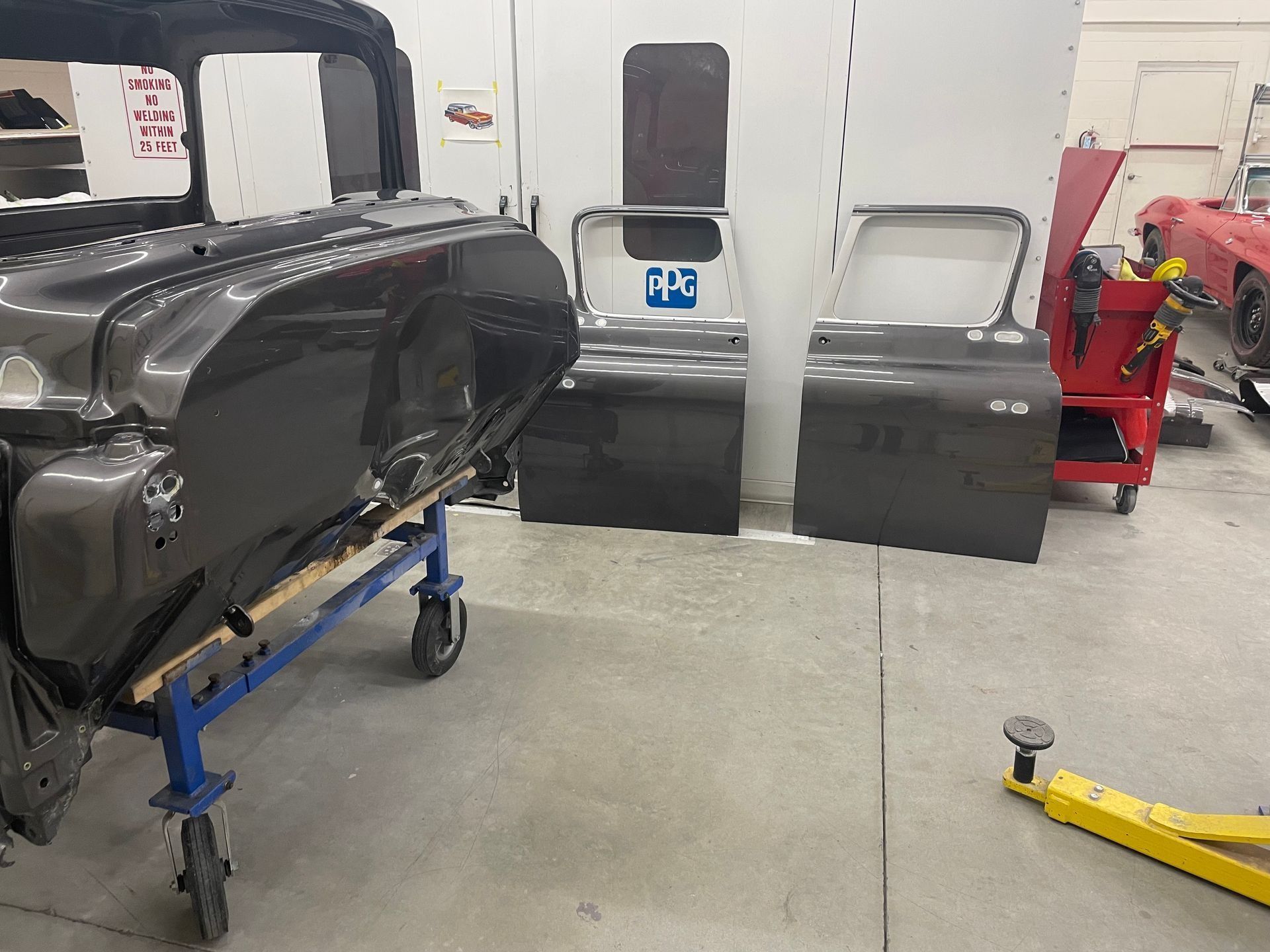 A car is sitting on a cart in a garage next to a red car.
