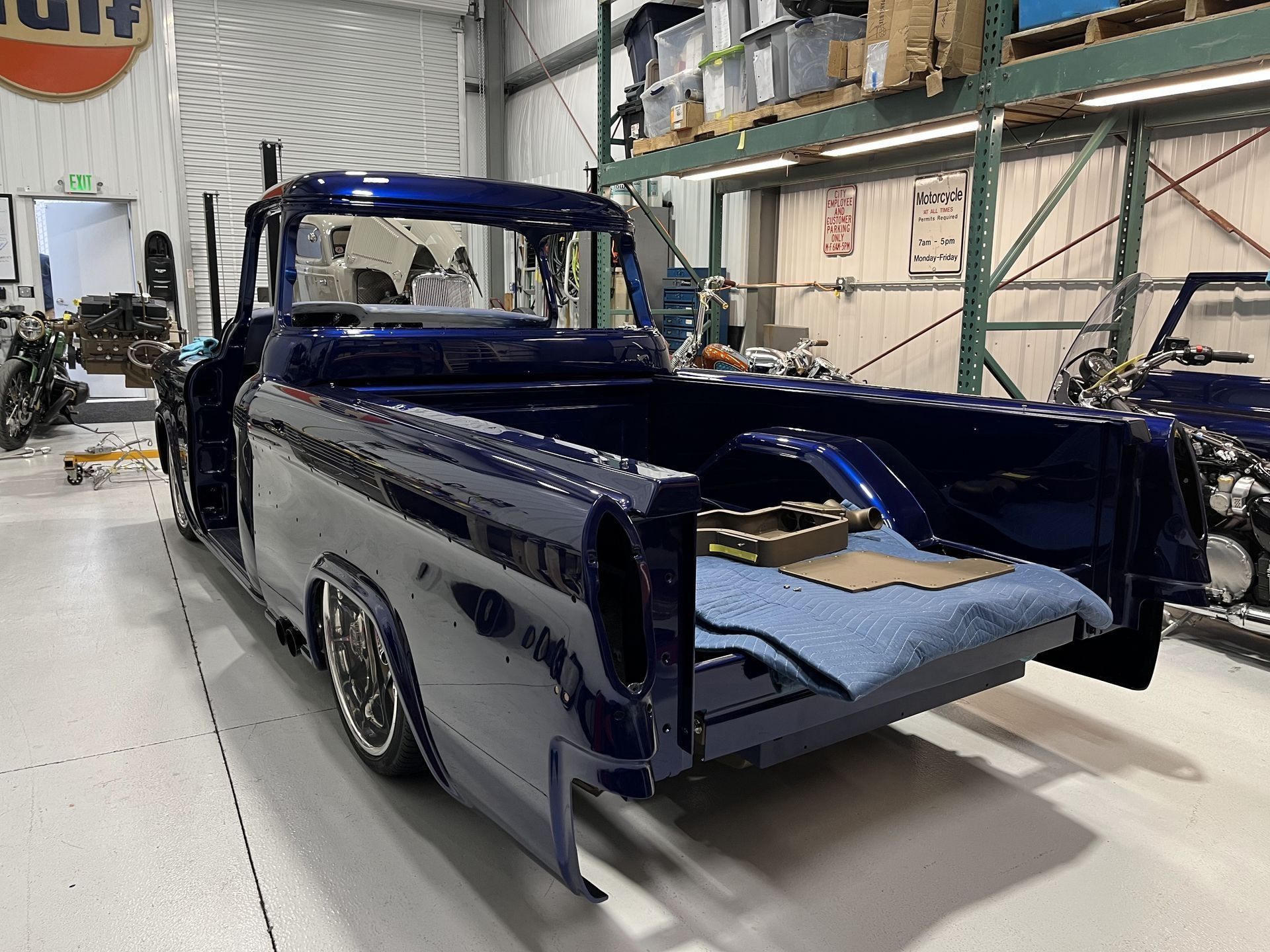 A blue truck is parked in a garage with the bed open.