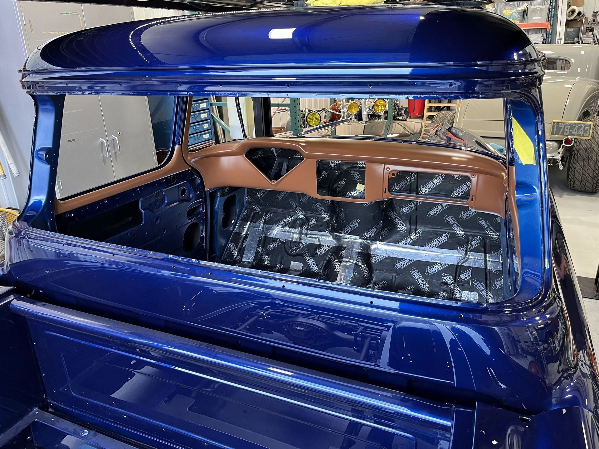 A blue truck with a broken windshield is sitting in a garage.
