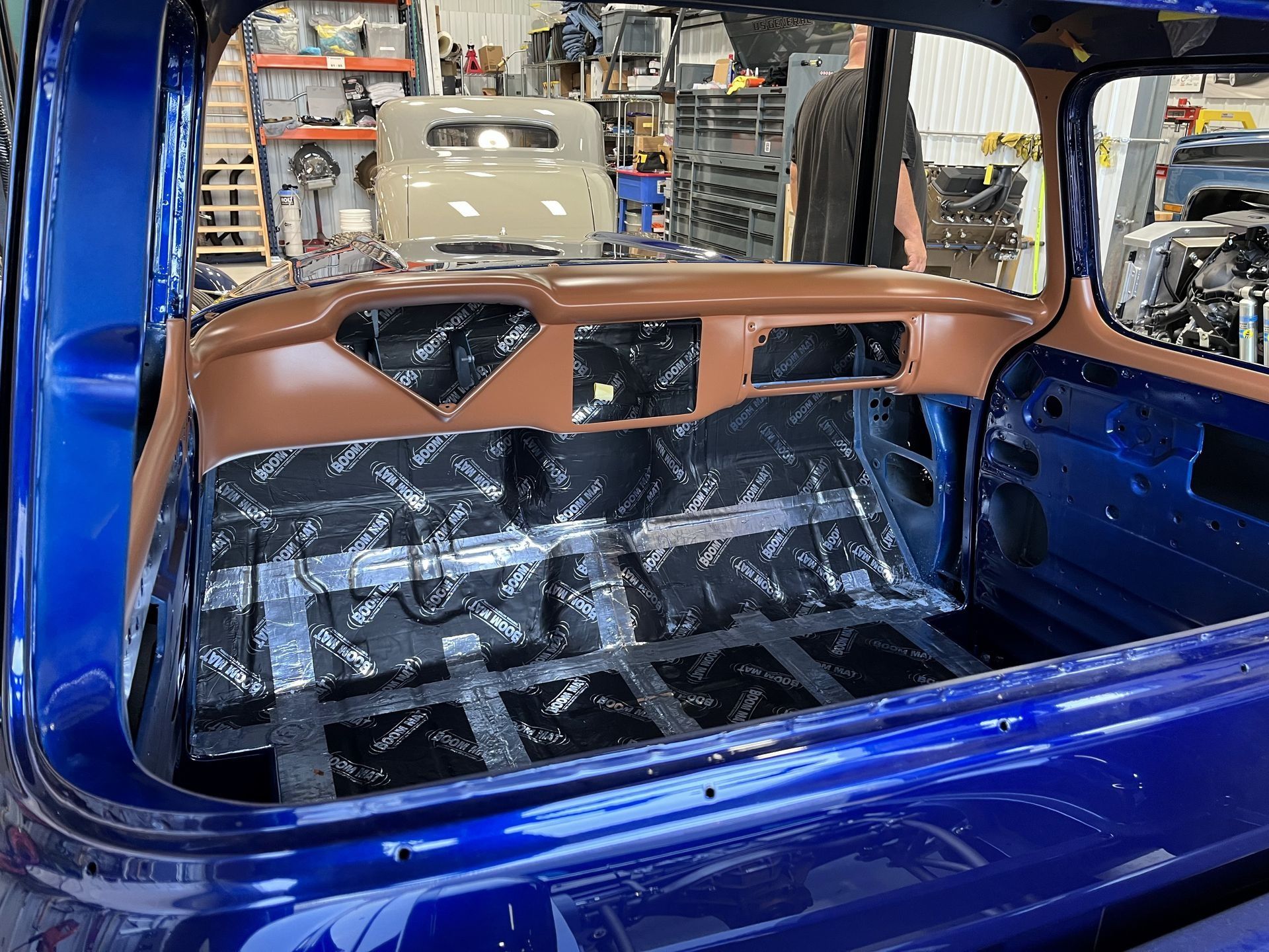The back of a blue car is being built in a garage.