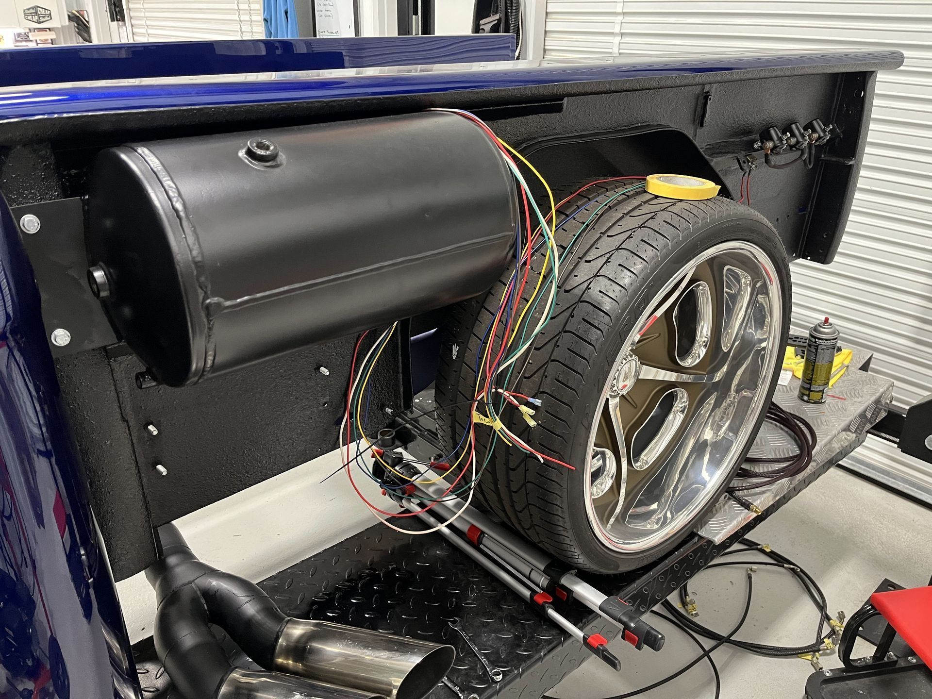 A blue truck is being worked on in a garage.