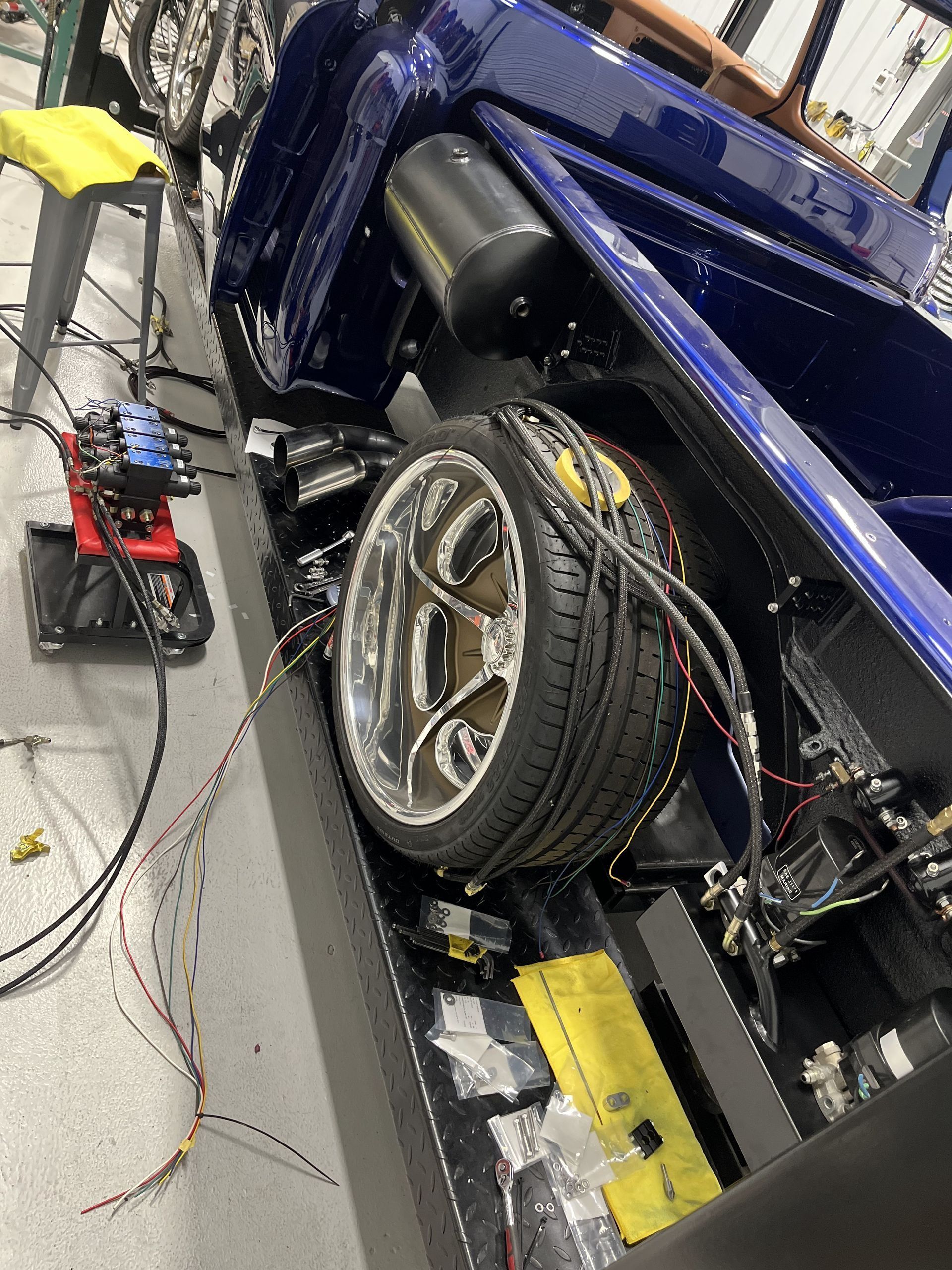 A blue car is being worked on in a garage.