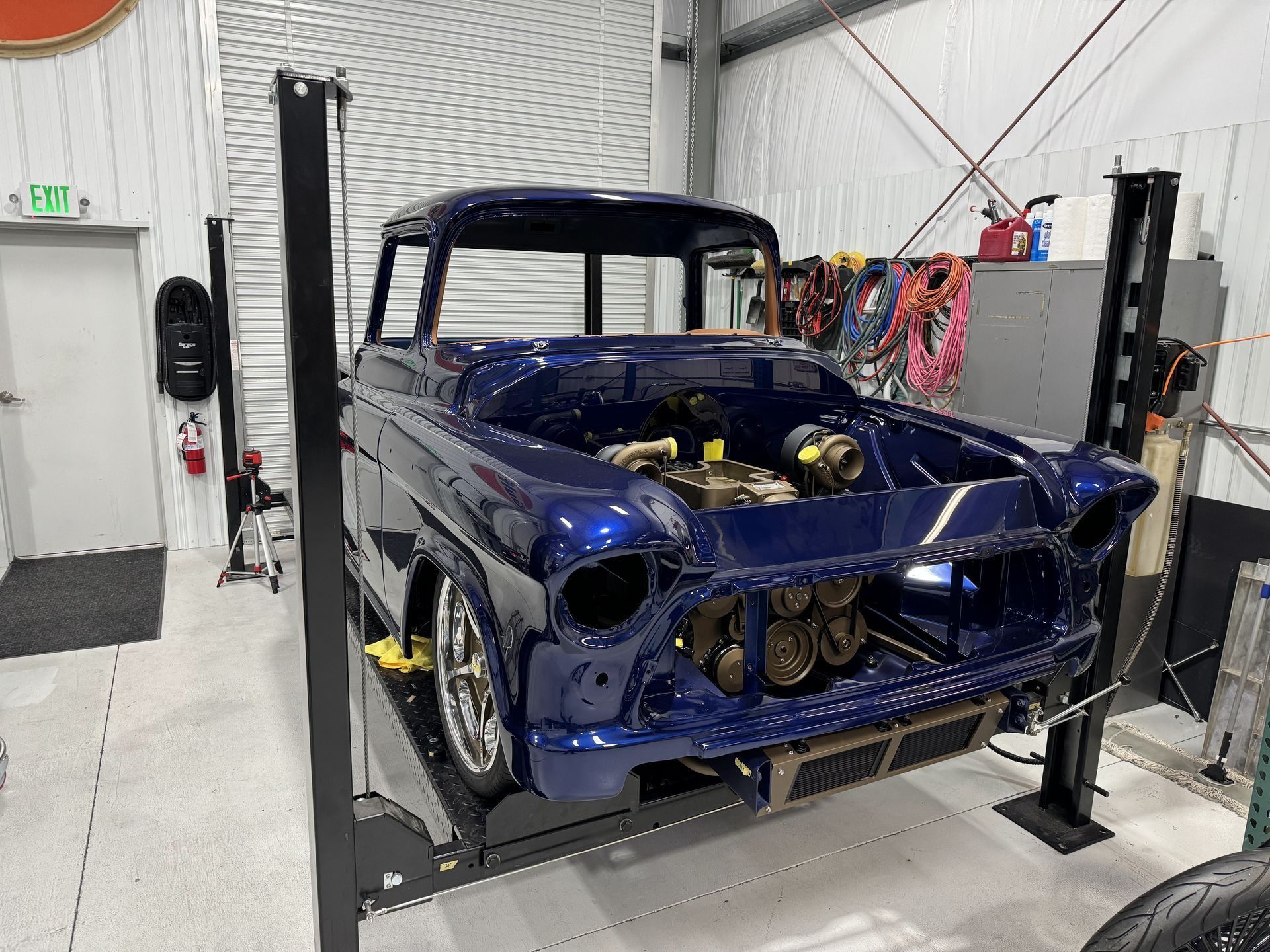 A blue truck is sitting on a lift in a garage.