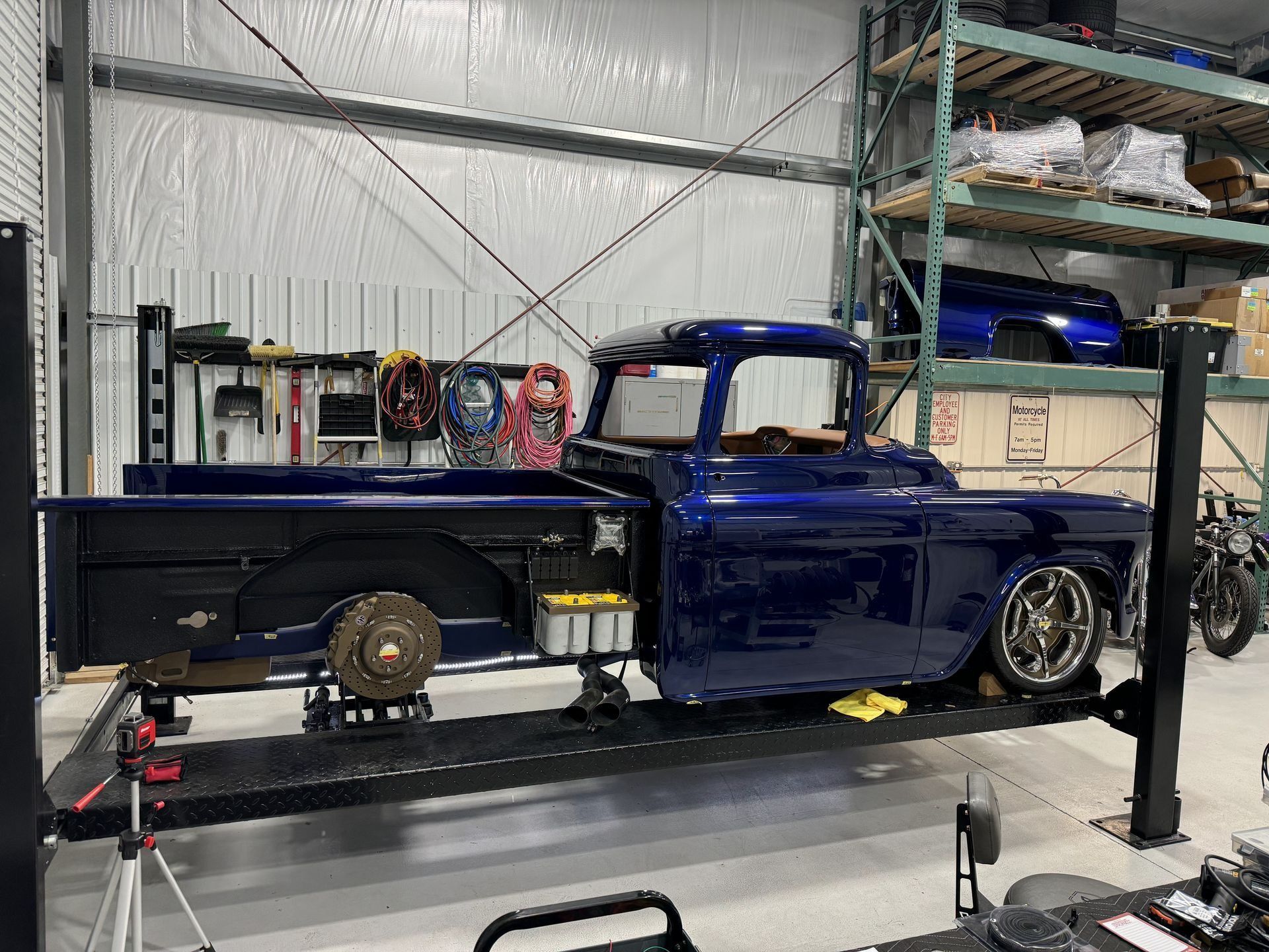 A blue truck is sitting on a lift in a garage.