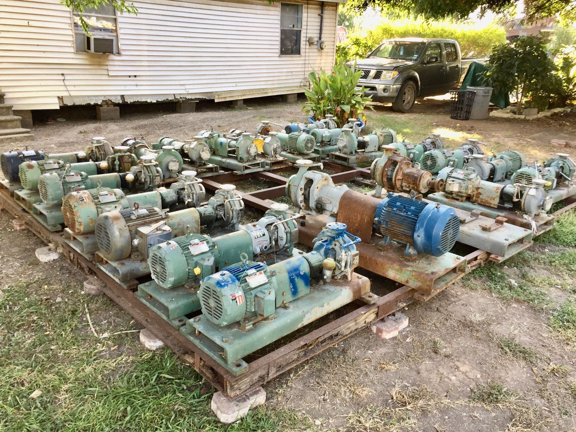 A bunch of pumps are sitting on a wooden pallet in front of a house.