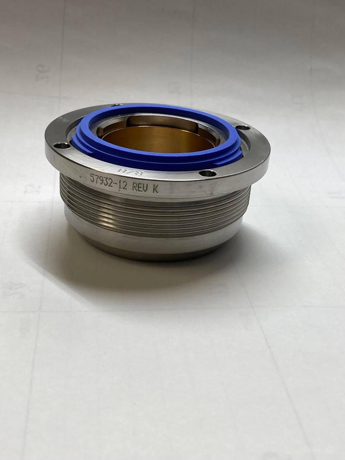 A metal object with a blue rubber seal on it is sitting on a white surface.