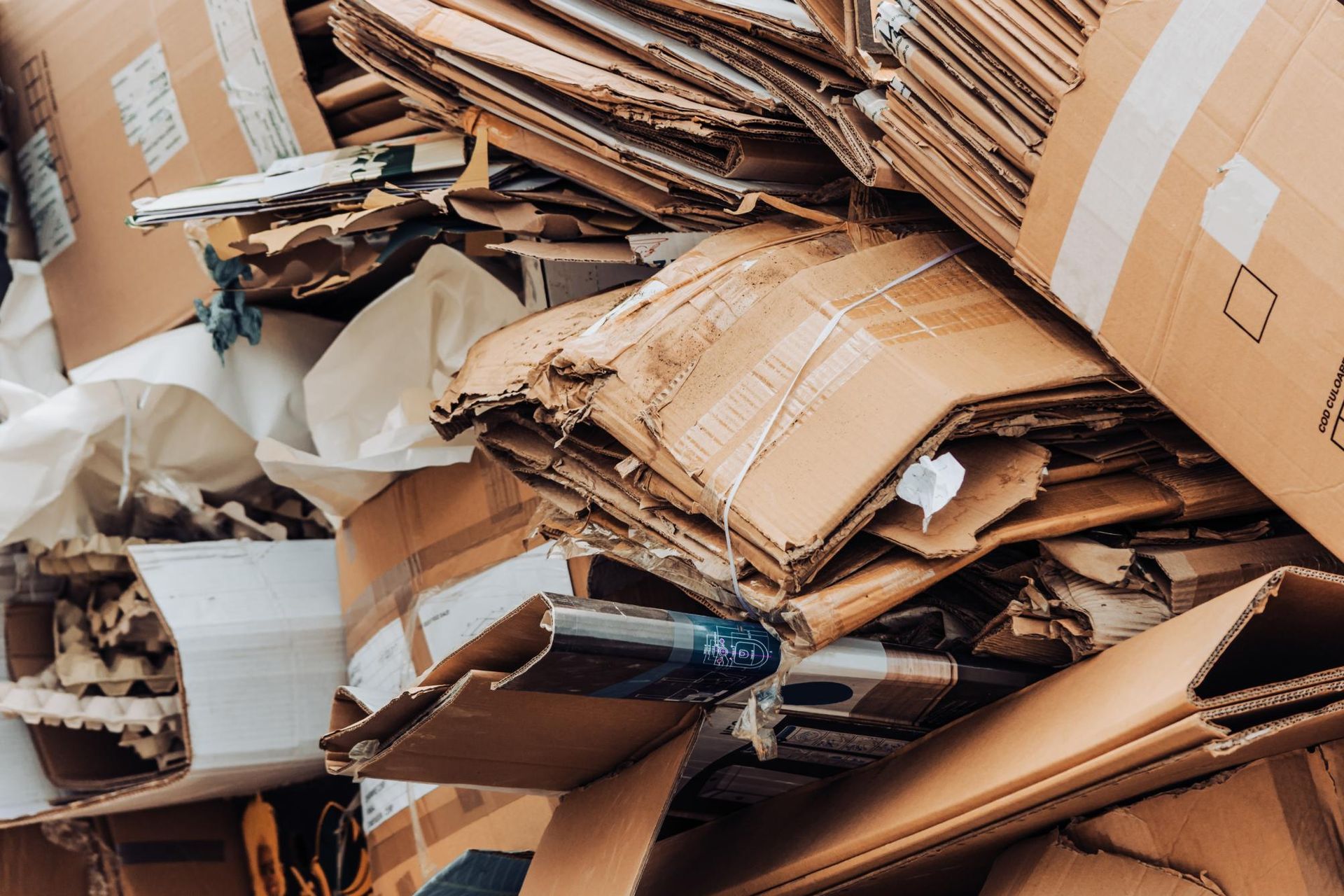 A large, cluttered pile of discarded, flattened brown cardboard boxes and packing material.