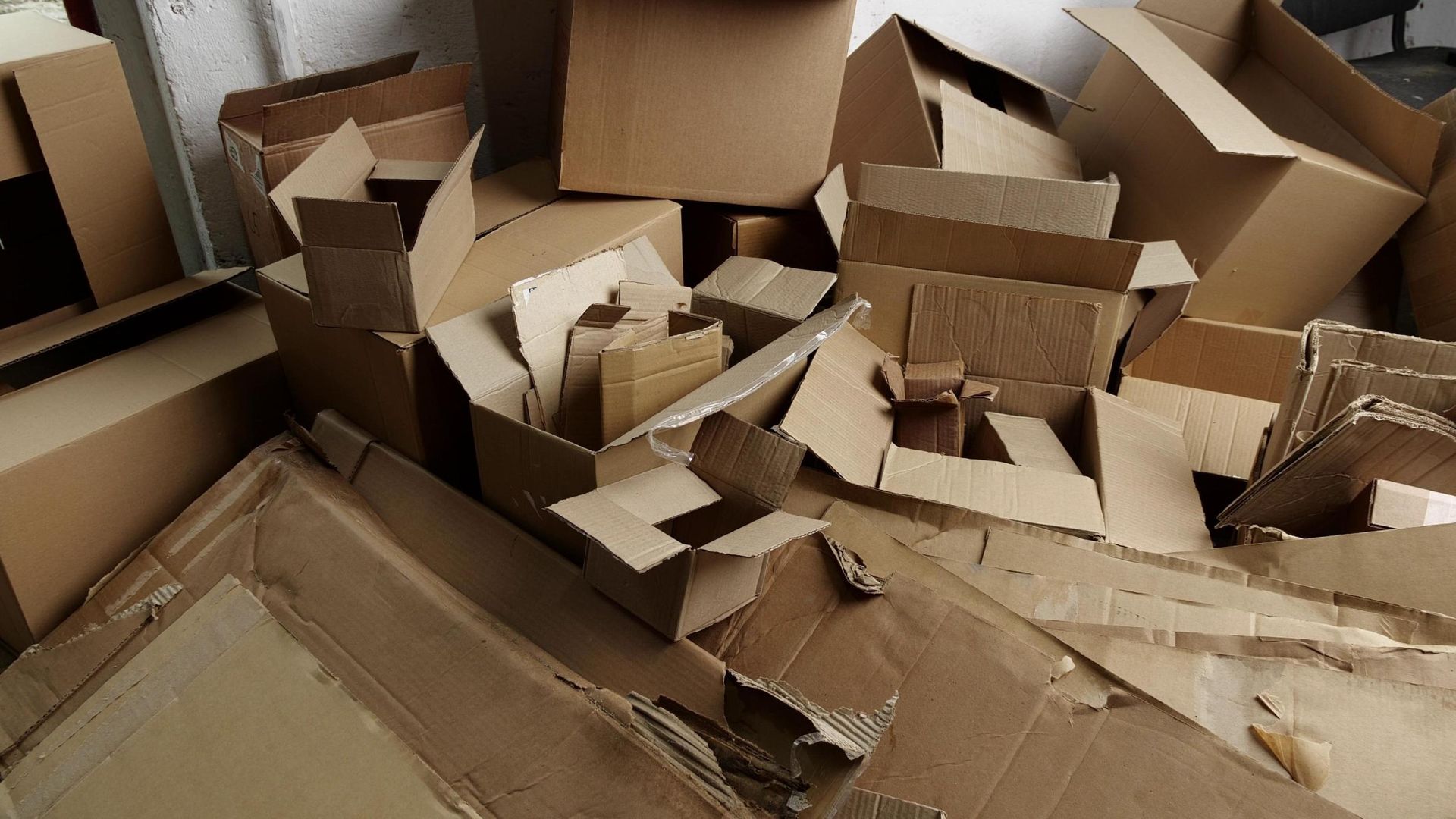 A pile of brown cardboard boxes of various sizes and shapes scattered on the floor.