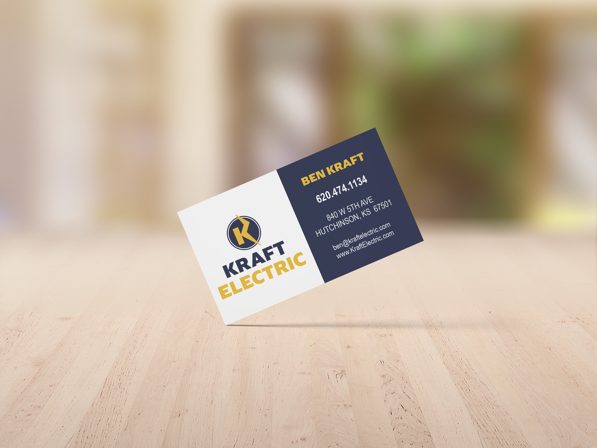 A business card for kraft electric is sitting on a wooden table.