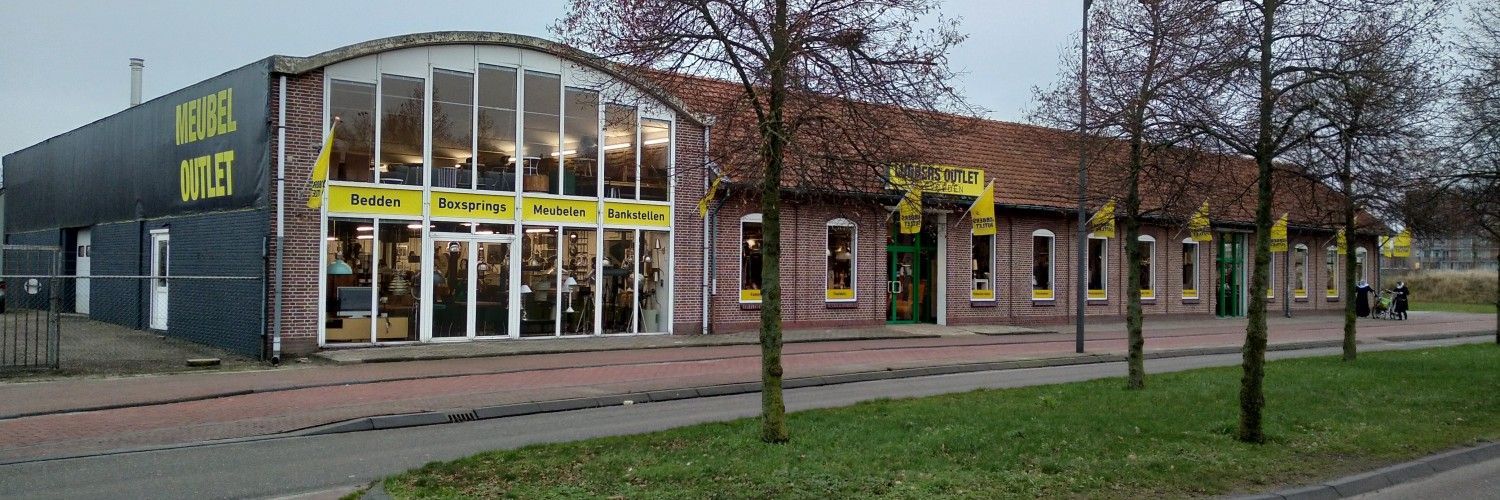 Een groot gebouw met veel ramen en bomen ervoor.