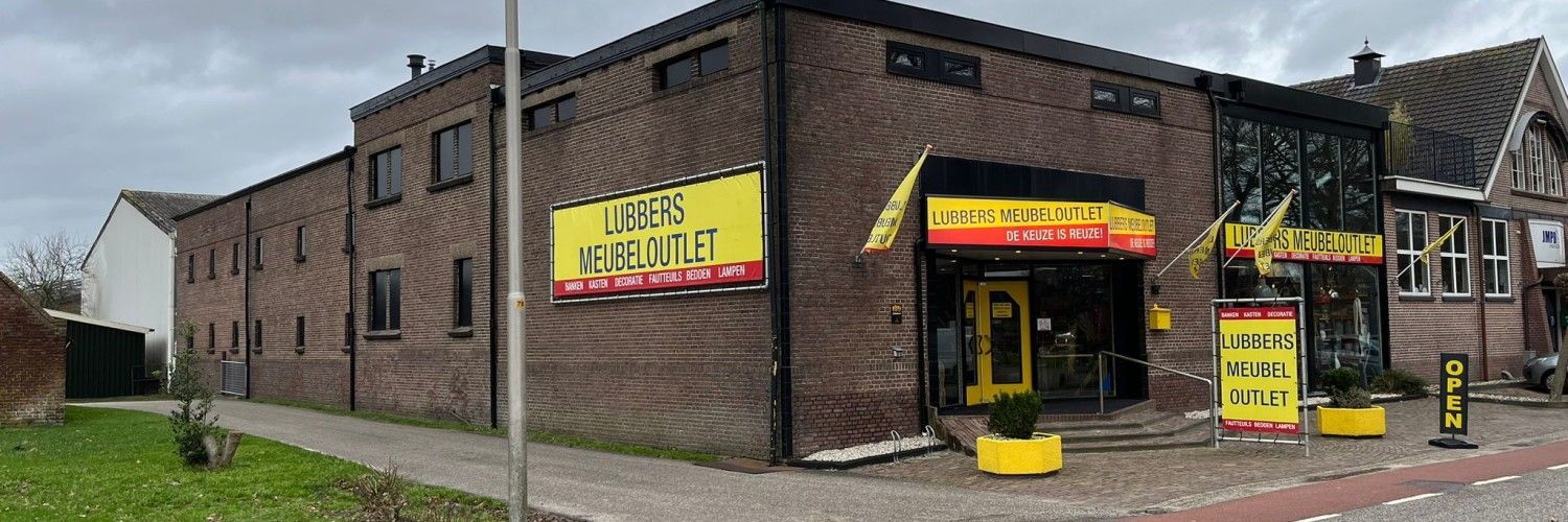 Een groot bakstenen gebouw met een geel bord aan de zijkant.